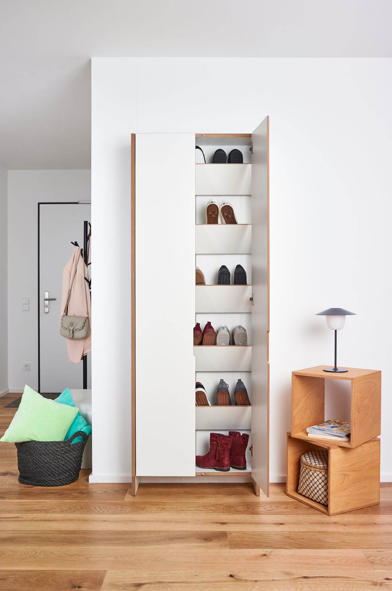 Tojo Flachmann Schuhschrank mit geöffneter Tür, gefüllt mit Schuhen, im modernen Eingangsbereich.