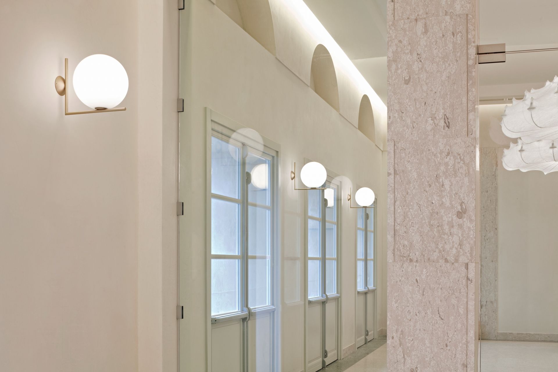 IC Lights Wandleuchte von Flos: Moderne Innenleuchte mit Kugel und goldenem Arm.