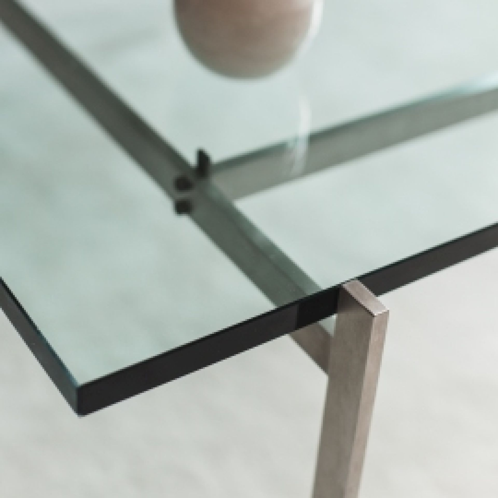 Detailaufnahme des PK 61 Couchtischs von Fritz Hansen mit Glasplatte und Stahlgestell, modernes Design.