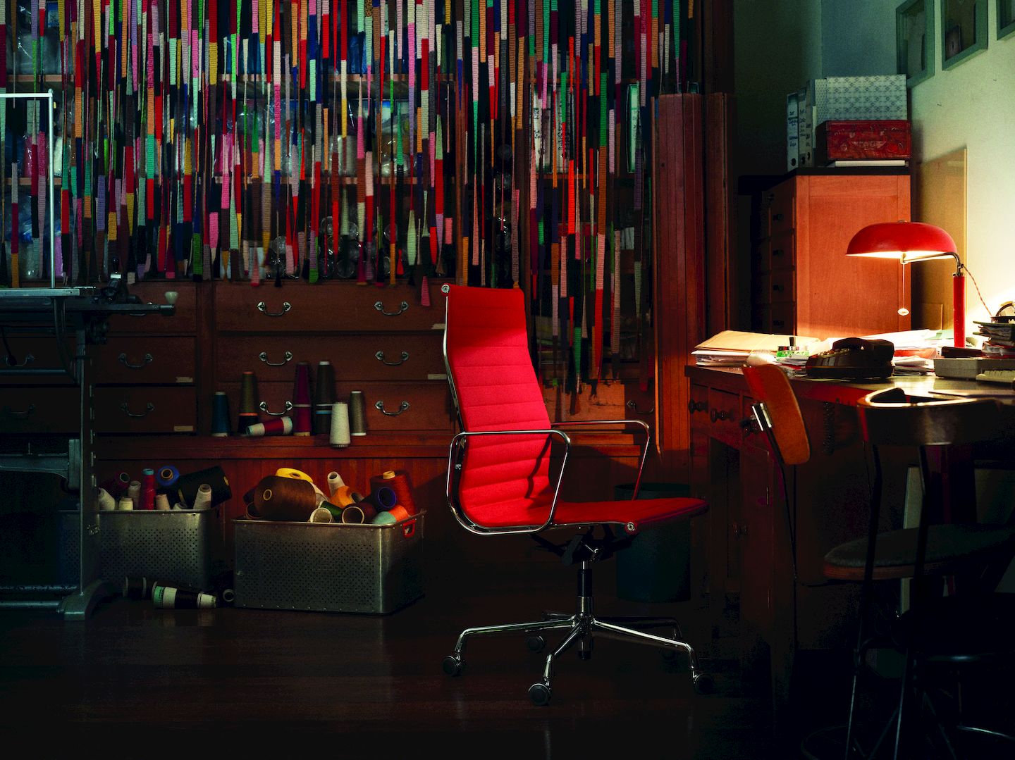 Roter Aluminium Chair EA 119 von Vitra in einem Schneideratelier mit Nähmaschine und Garn.