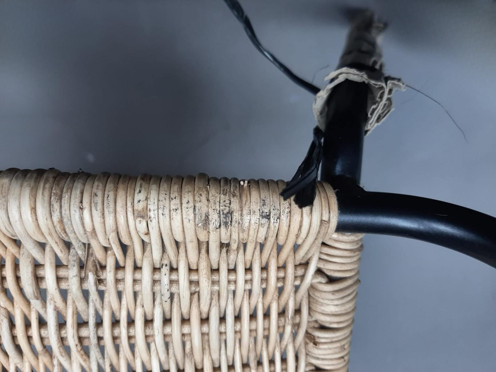 Detailaufnahme eines Richard Lampert Stuhls TT 54 (Mängelexemplar) mit Rattan-Geflecht und schwarzem Metallgestell.