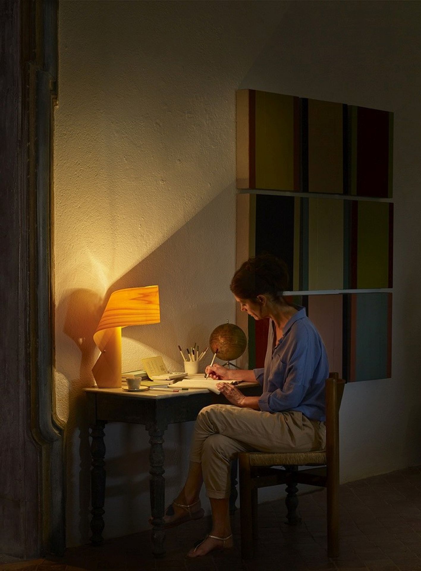 Frau am Schreibtisch mit orangefarbener Air Table Tischleuchte von LZF Lamps für stimmungsvolle Beleuchtung.