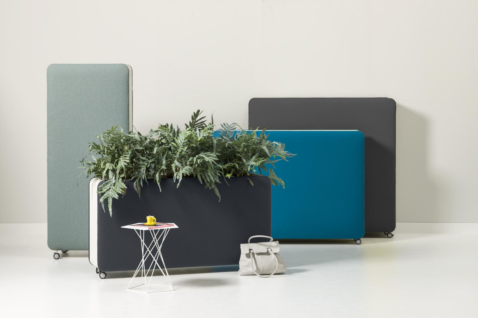 Cascando Pillow Space Akustik-Raumteiler in verschiedenen Farben mit Pflanzen, Tisch und Tasche im modernen Büro.