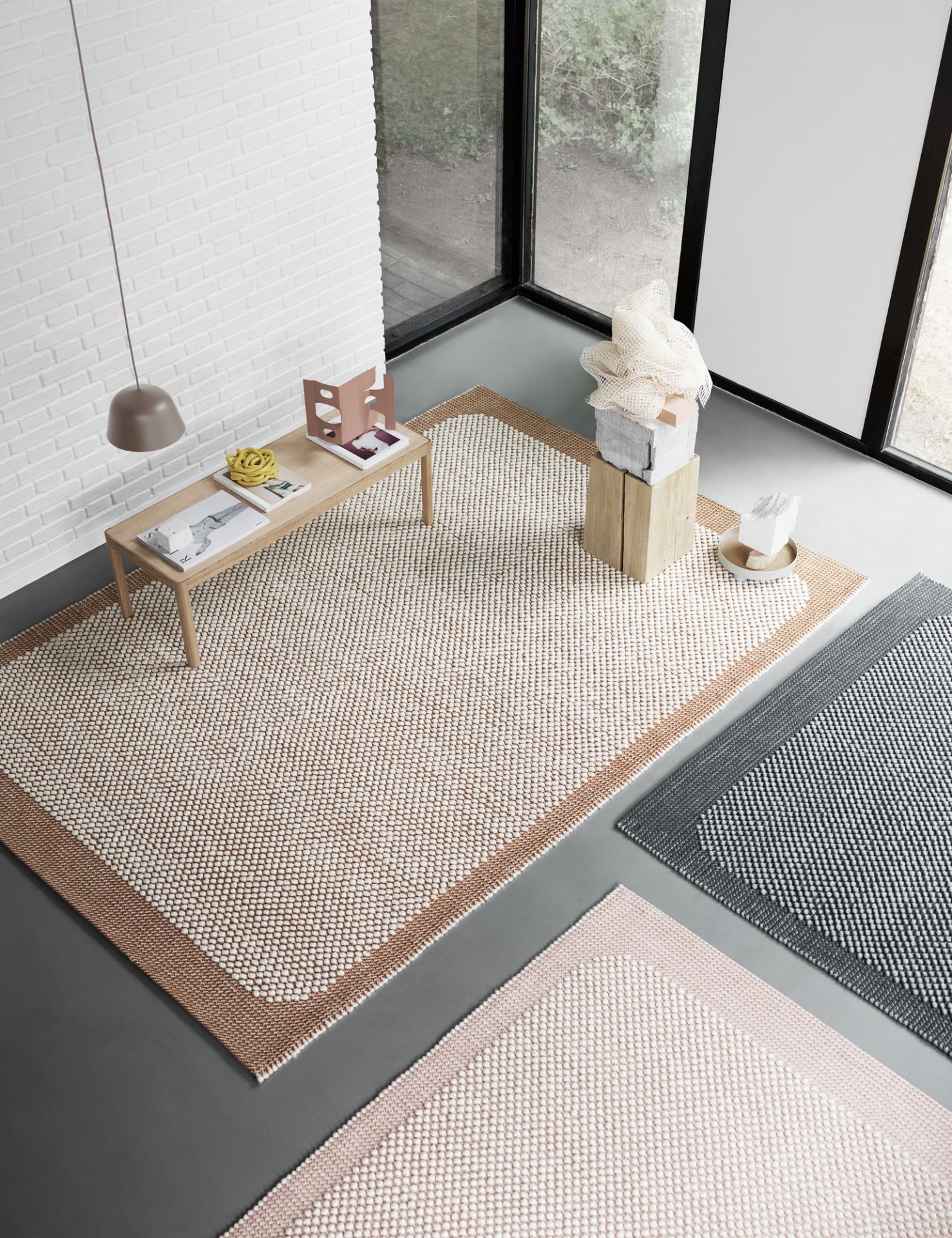 Draufsicht von drei Teppichen, darunter der Muuto Workshop Coffee Table Couchtisch, in einem hellen, modernen Raum.