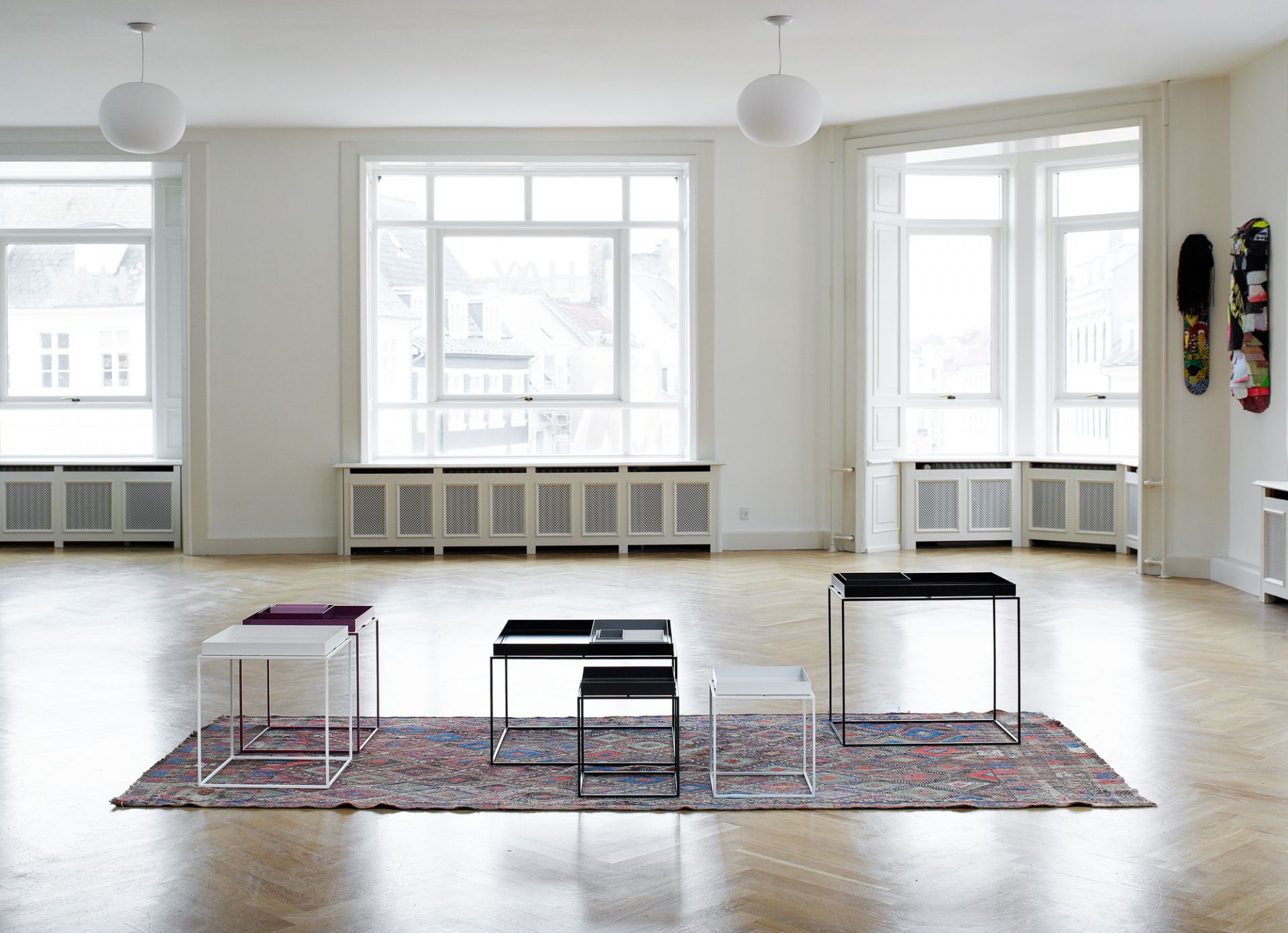 Helle Raumansicht mit vier Tray Table M Tischen von Hay in Schwarz, Weiß und Lila.