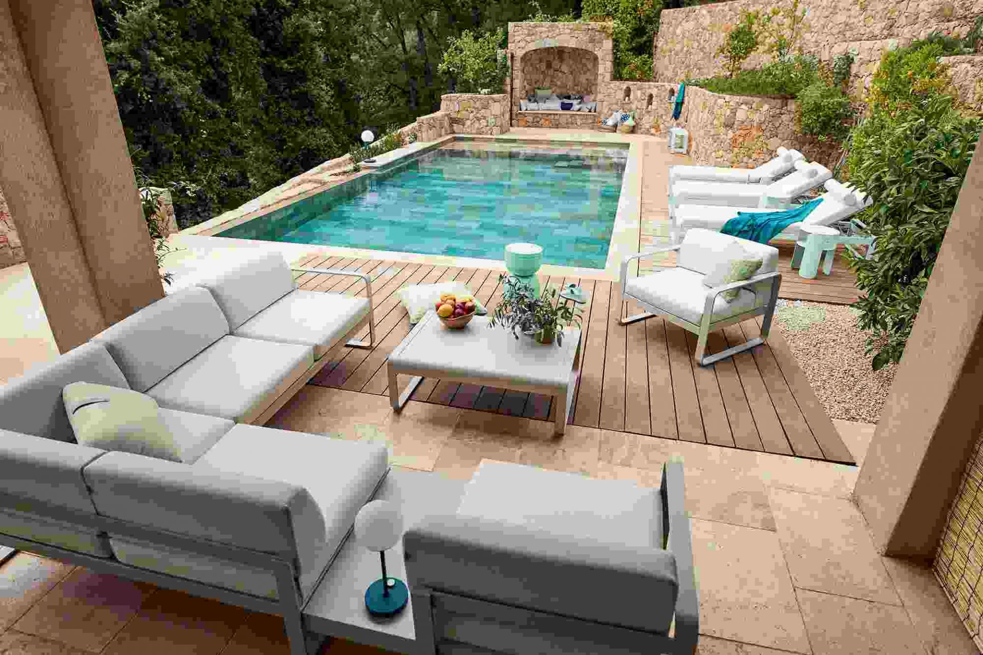 Bellevie Sonnenliege von Fermob am Pool: Elegante Gartenmöbel für entspannte Stunden im Freien.