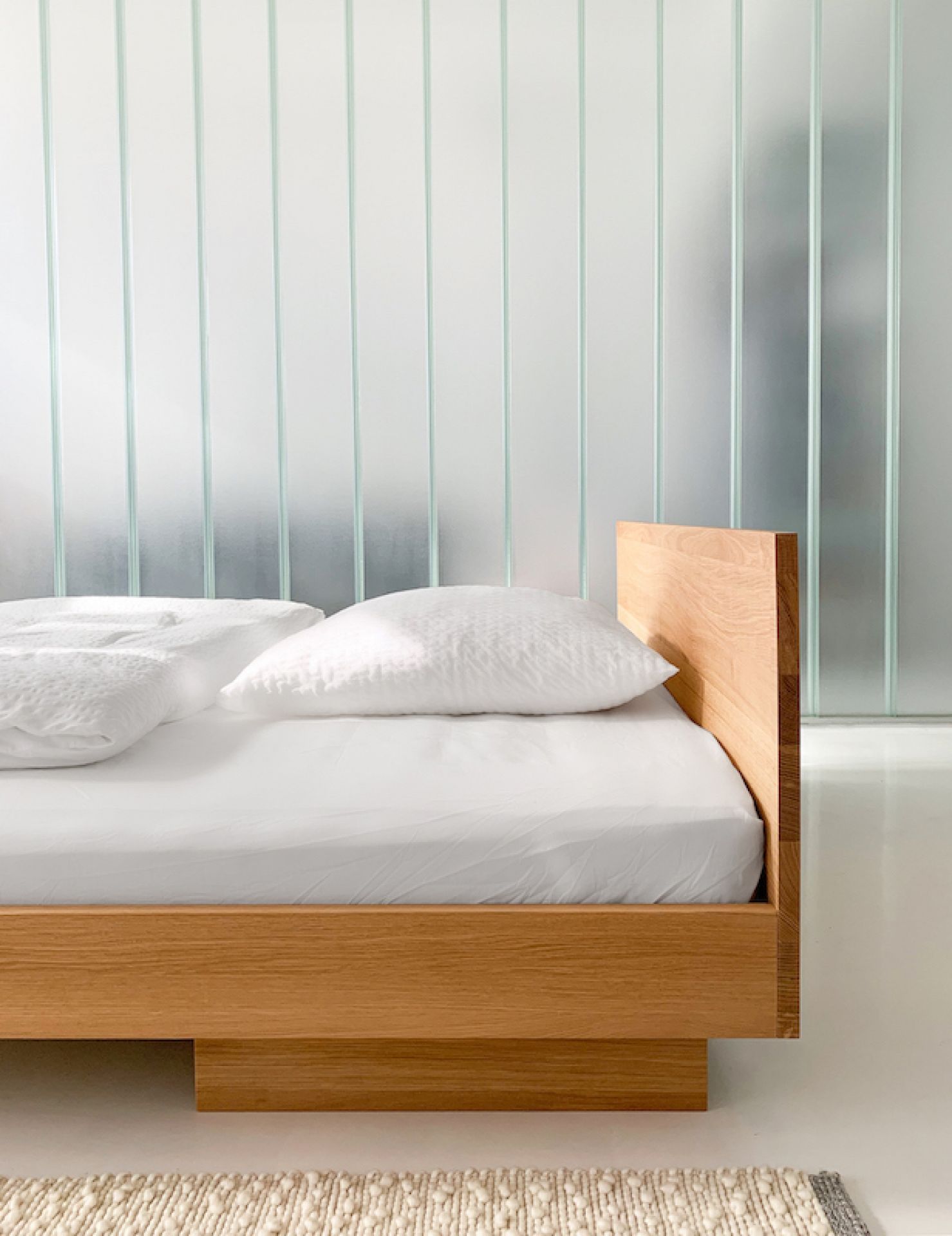 ZIANS Bett Large aus hellem Holz mit Kopfteil und weißer Bettwäsche im Schlafzimmer.