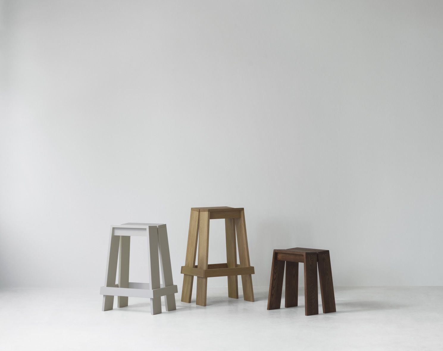 Drei Let Barhocker von Normann Copenhagen in Grau, Eiche und Dunkelbraun vor weißem Hintergrund.