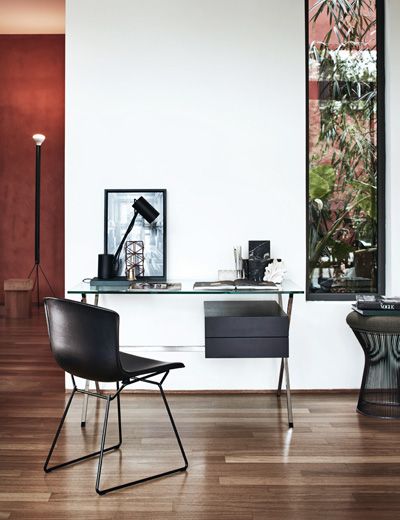 Schwarzer Bertoia Stuhl mit Kernlederbezug vor einem modernen Schreibtisch im minimalistischen Interieur.