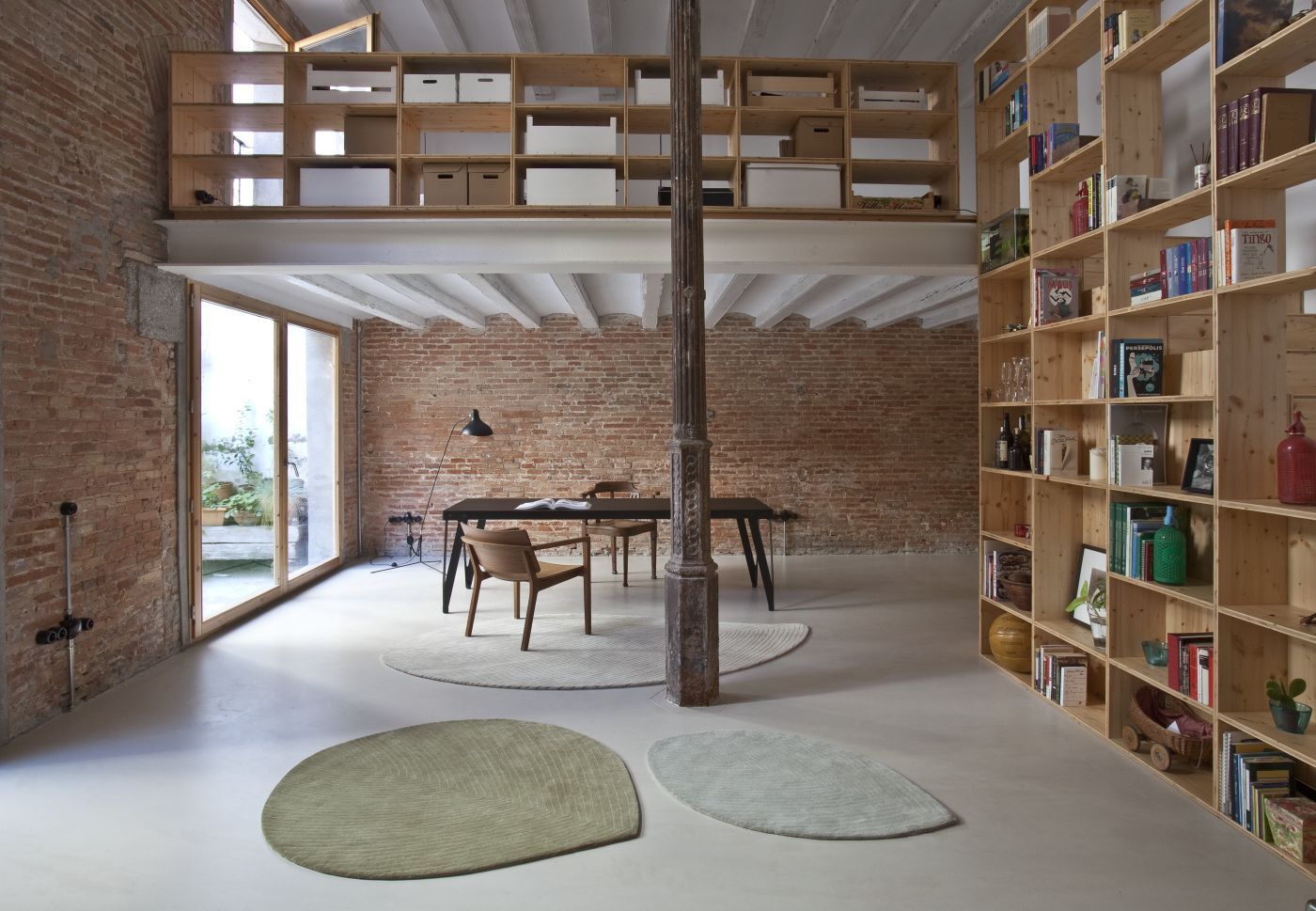 Zwei Quill Teppiche von Nanimarquina in einem Loft mit Backsteinwand und Holzbücherregal.