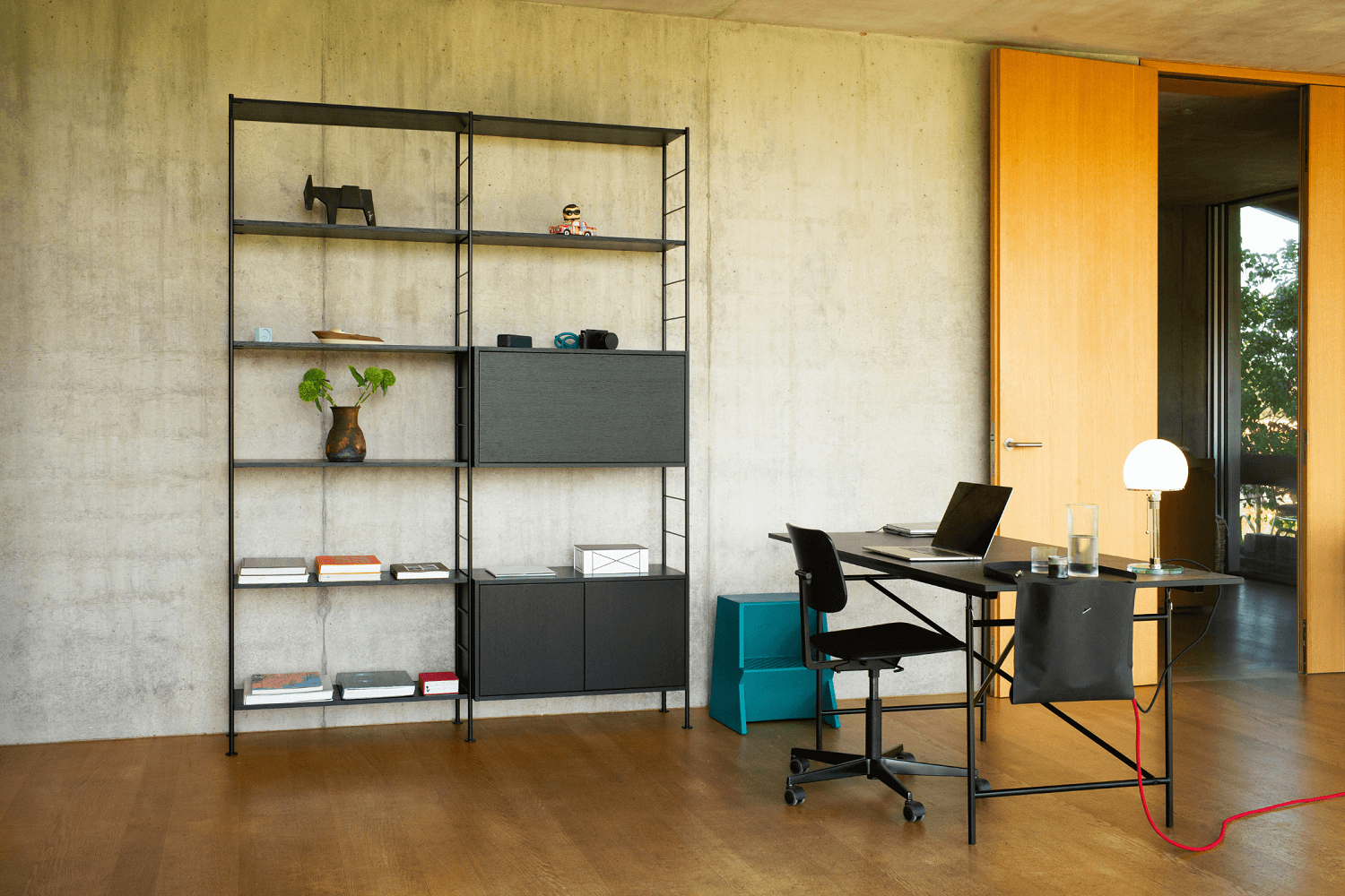 Eiermann Tisch mit silbernem Gestell und Kreuzstreben in modernem Arbeitszimmer mit Regalsystem.