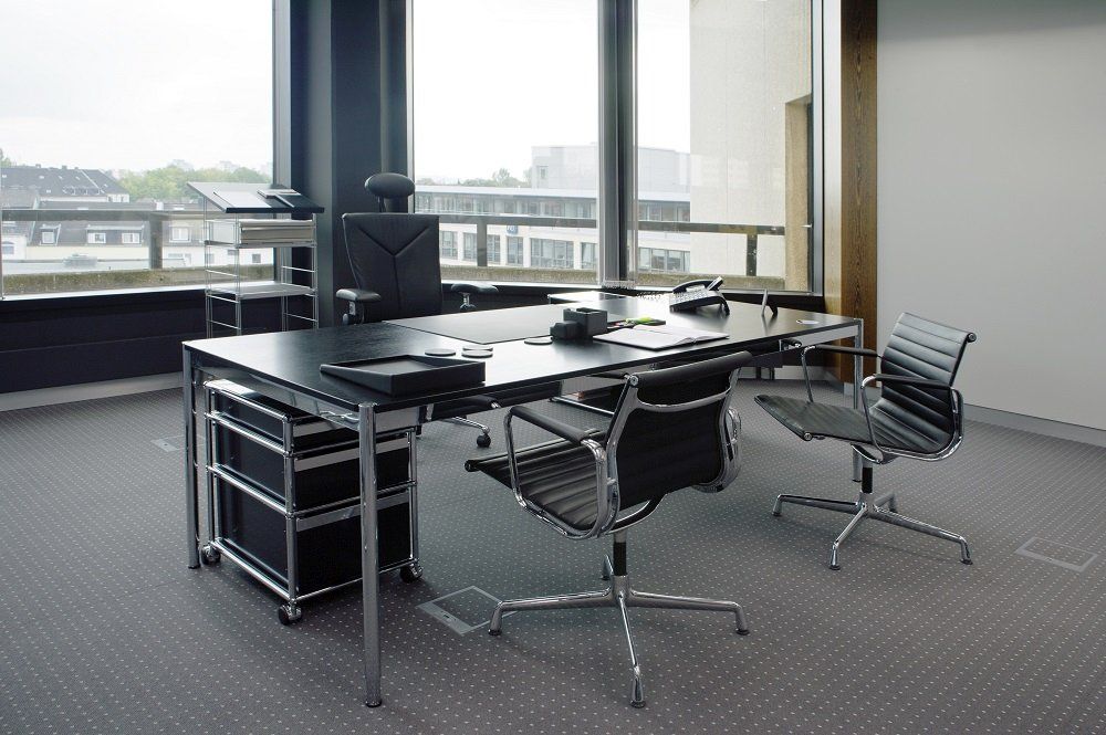 USM Haller Rollcontainer mit drei Schubladen unter einem Schreibtisch in einem modernen Büro.