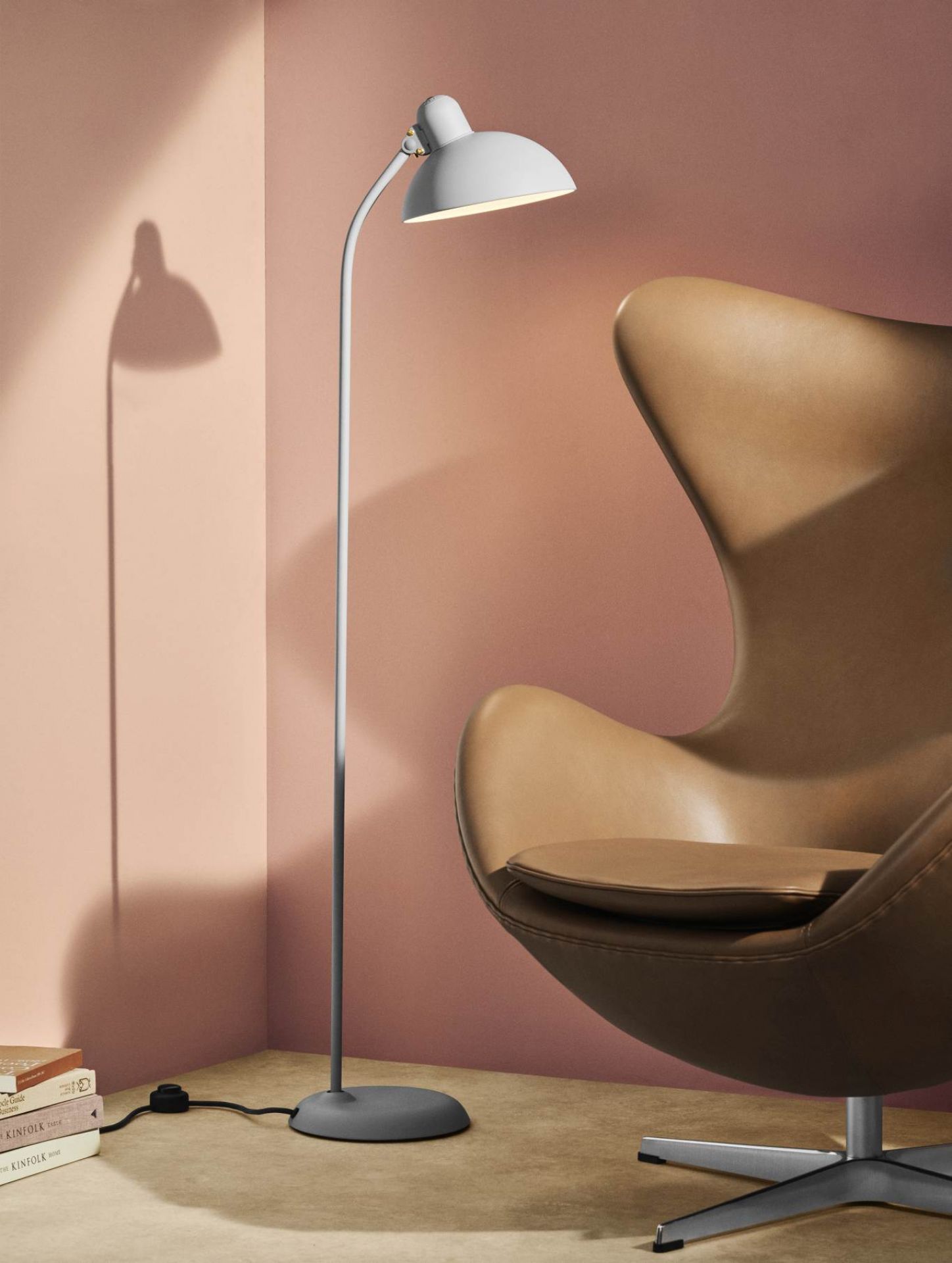 Graue Kaiser idell Stehleuchte 6556 F von Fritz Hansen neben braunem Sessel. Designleuchte für Wohnzimmer.