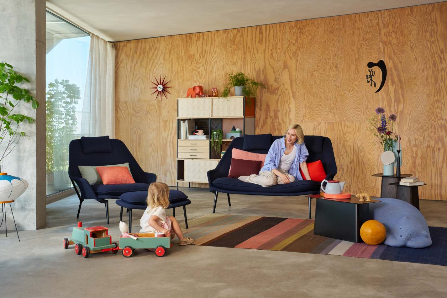 Vitra Slow Sofa und Sessel in blauem Stoffbezug in modernem Wohnzimmer mit Frau und Kind.