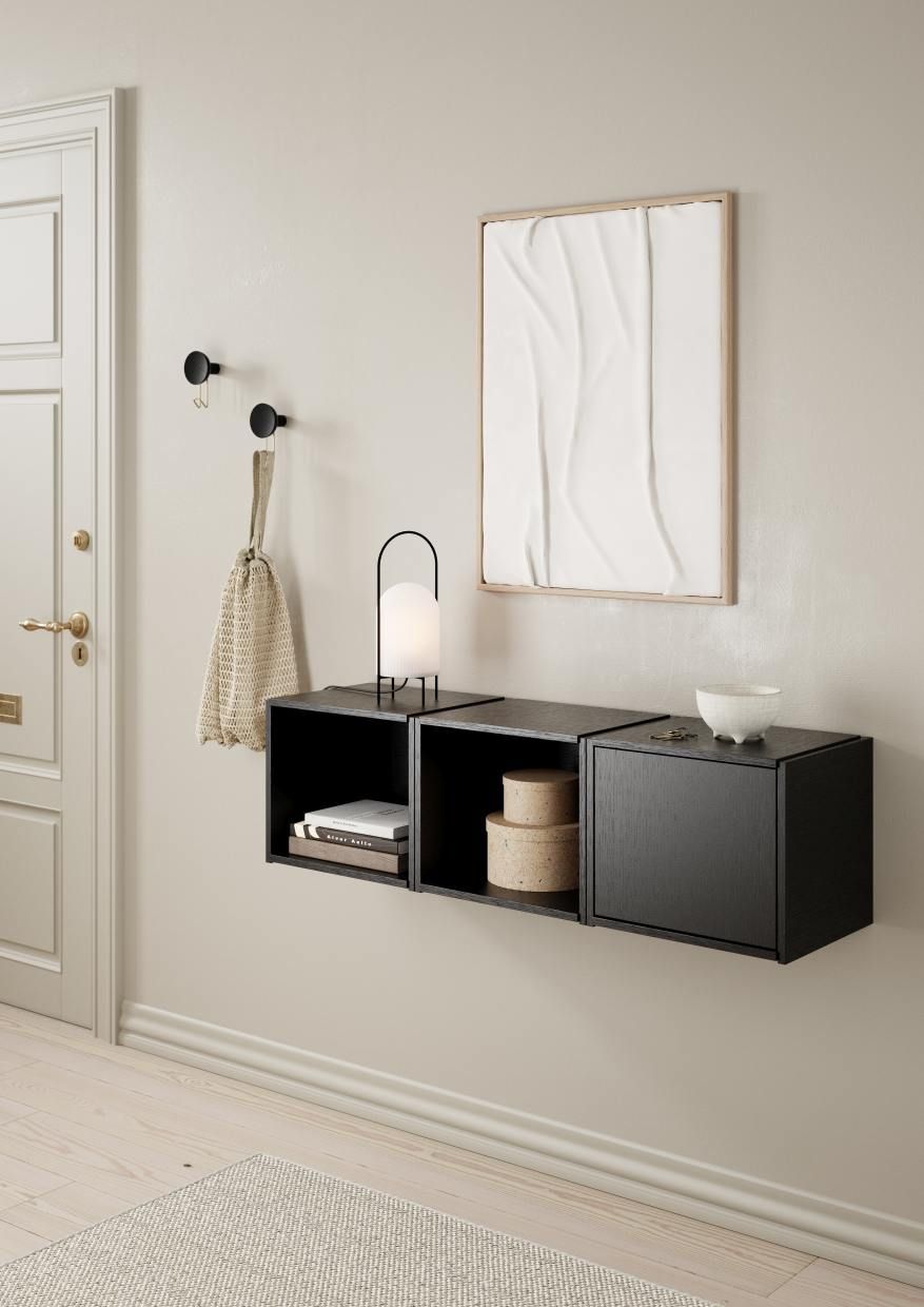 Schwarzes Bricks System Regal an der Wand mit Lampe, Deko und Tür im Flur.