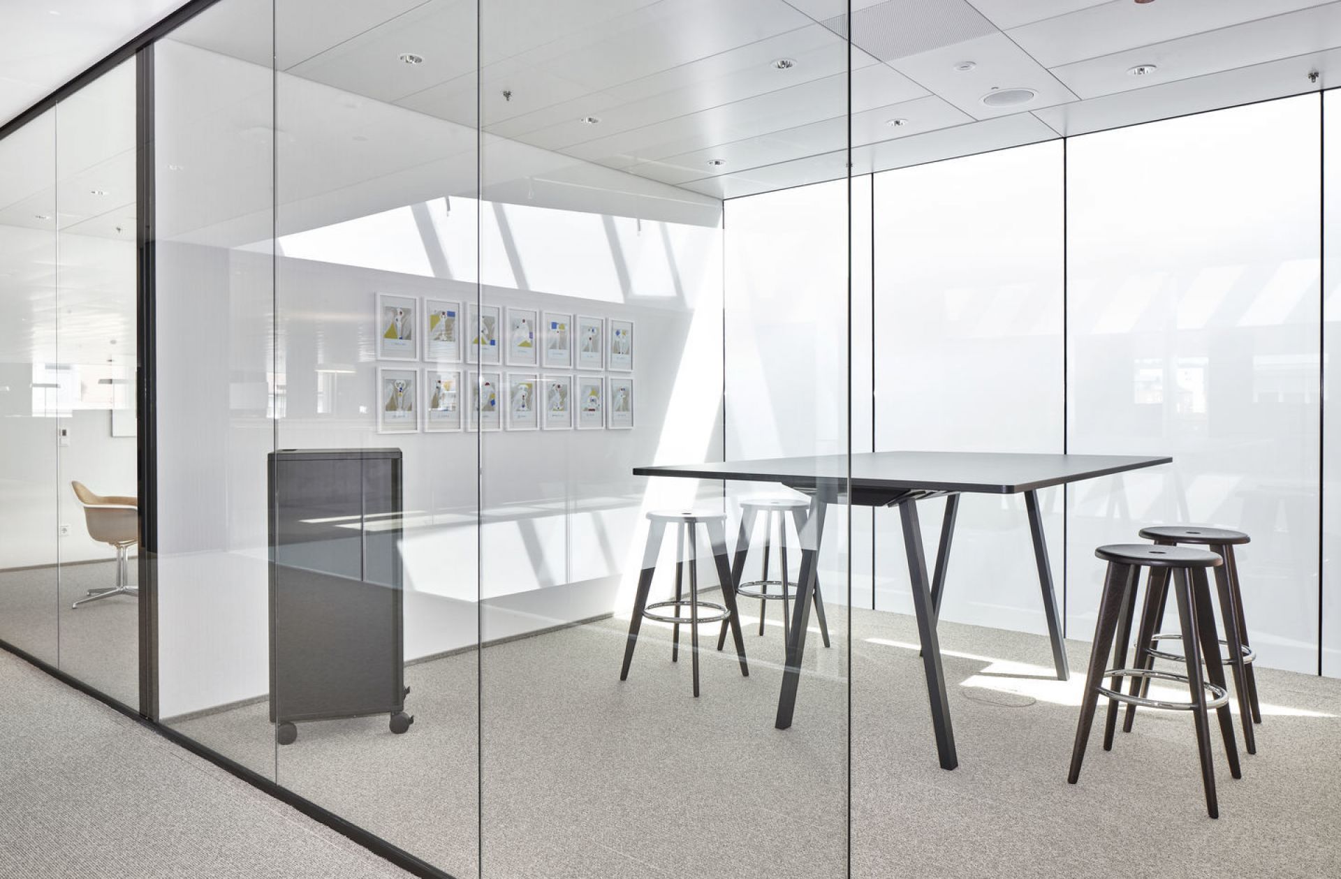 Moderner Konferenzraum mit schwarzem Tisch und Vitra Tabouret Haut Barhockern in Weiß und Dunkelbraun.