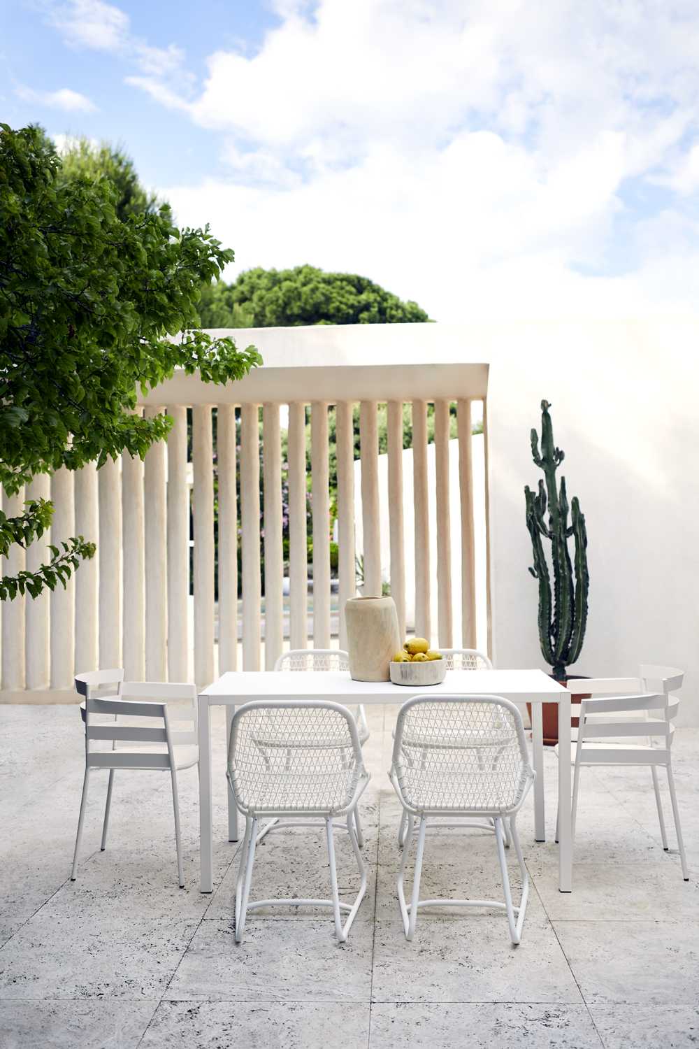 Weißer Sixties Outdoor Stuhl von Fermob mit passendem Tisch und Dekoration im Garten.