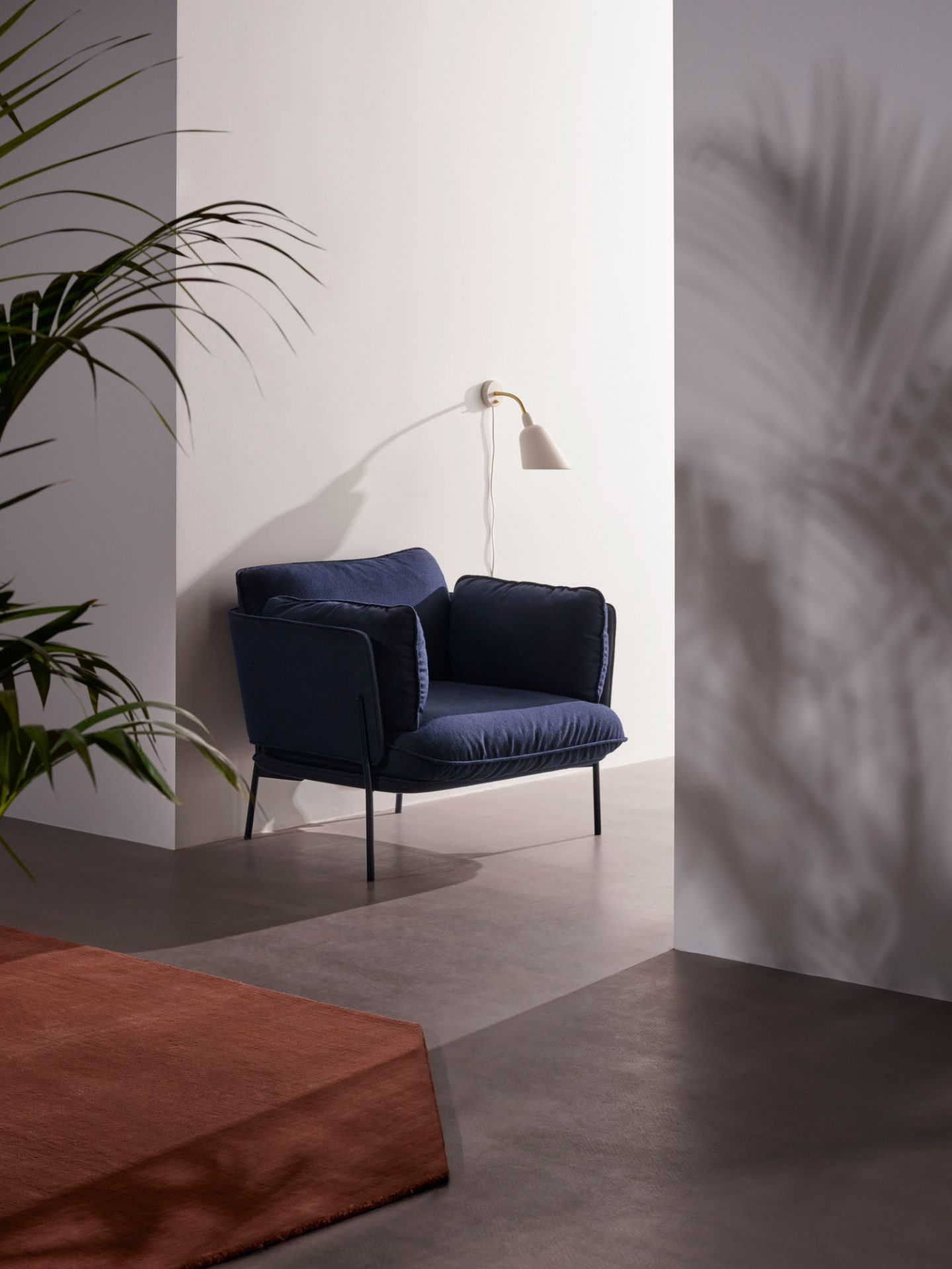 Blauer Cloud Sessel von AndTradition mit dunklem Metallgestell in modernem Ambiente.