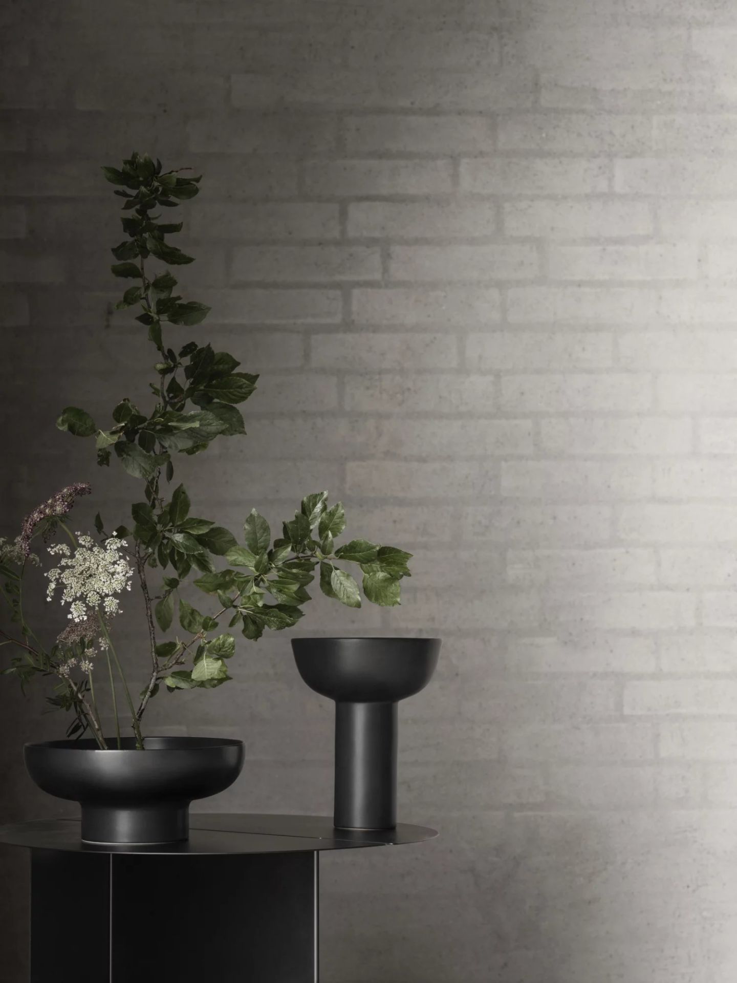 Oru Beistelltisch von Blomus in Burned Metal Optik mit Blumen und Dekoration.