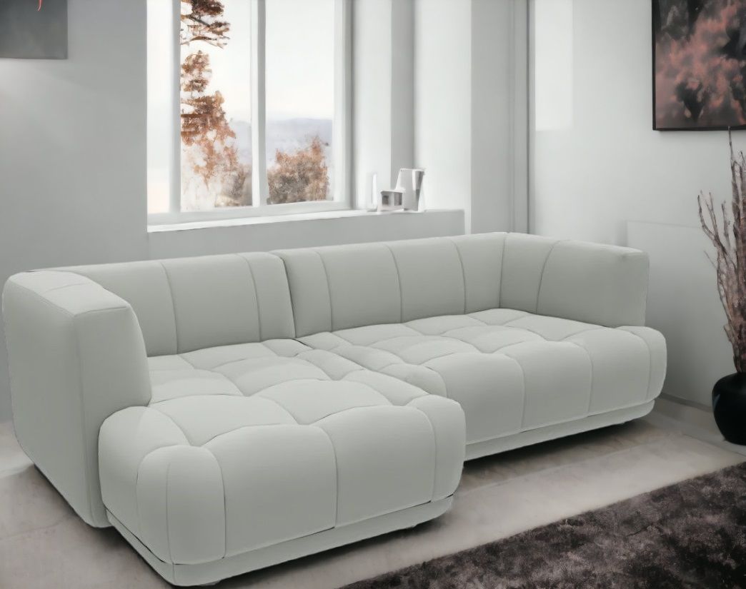 Helles Quilton Sofa von Hay mit Chaiselongue und gesteppter Sitzfläche vor einem Fenster.