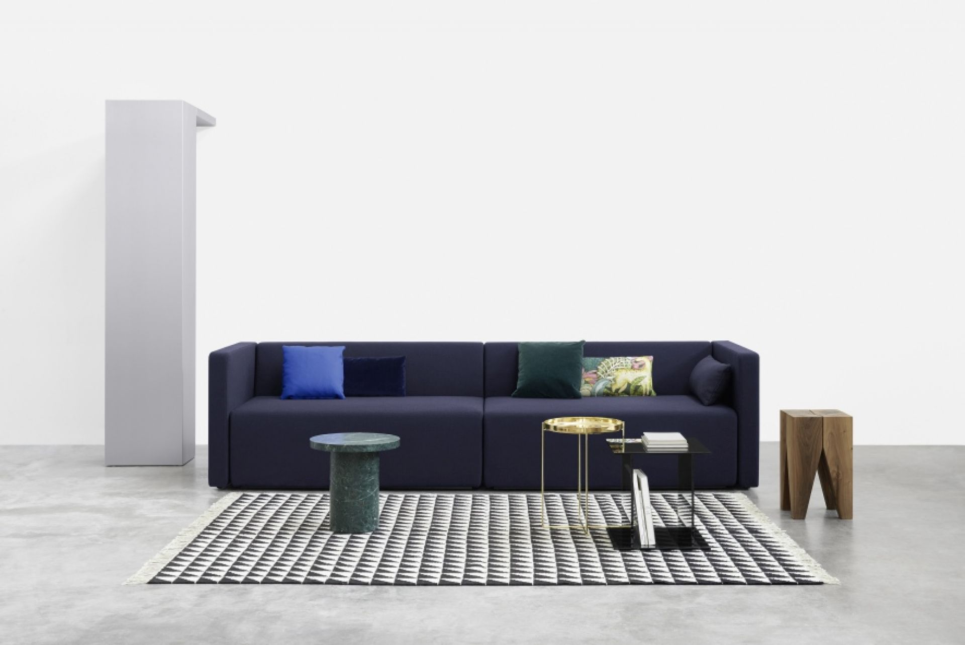 SF06 Kerman Modulsofa von e15 in Dunkelblau mit Kissen und Beistelltischen auf Teppich.