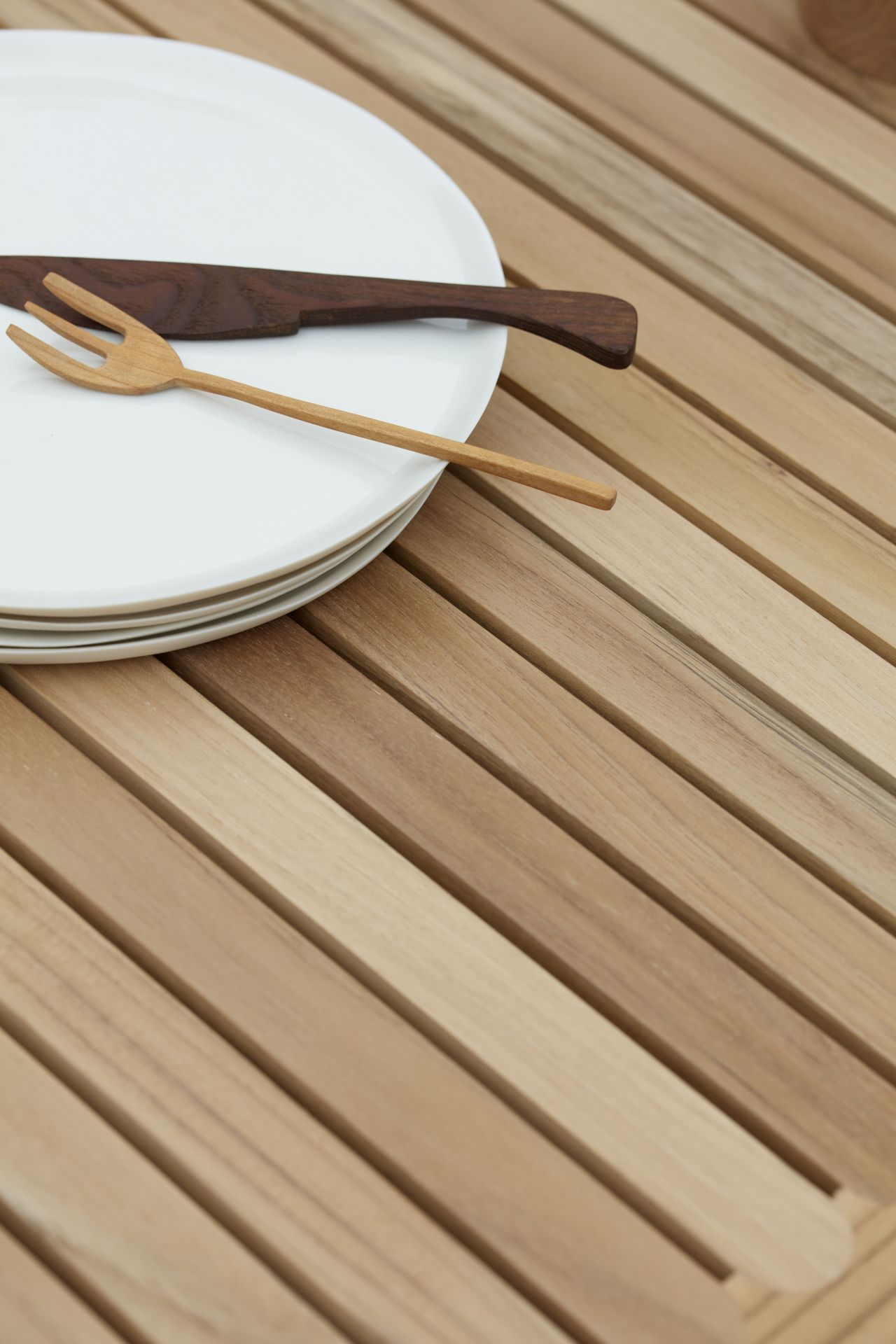 Detailaufnahme des Carl Hansen AH902 Outdoor Esstisches aus Teakholz mit Tellern und Holz-Besteck.