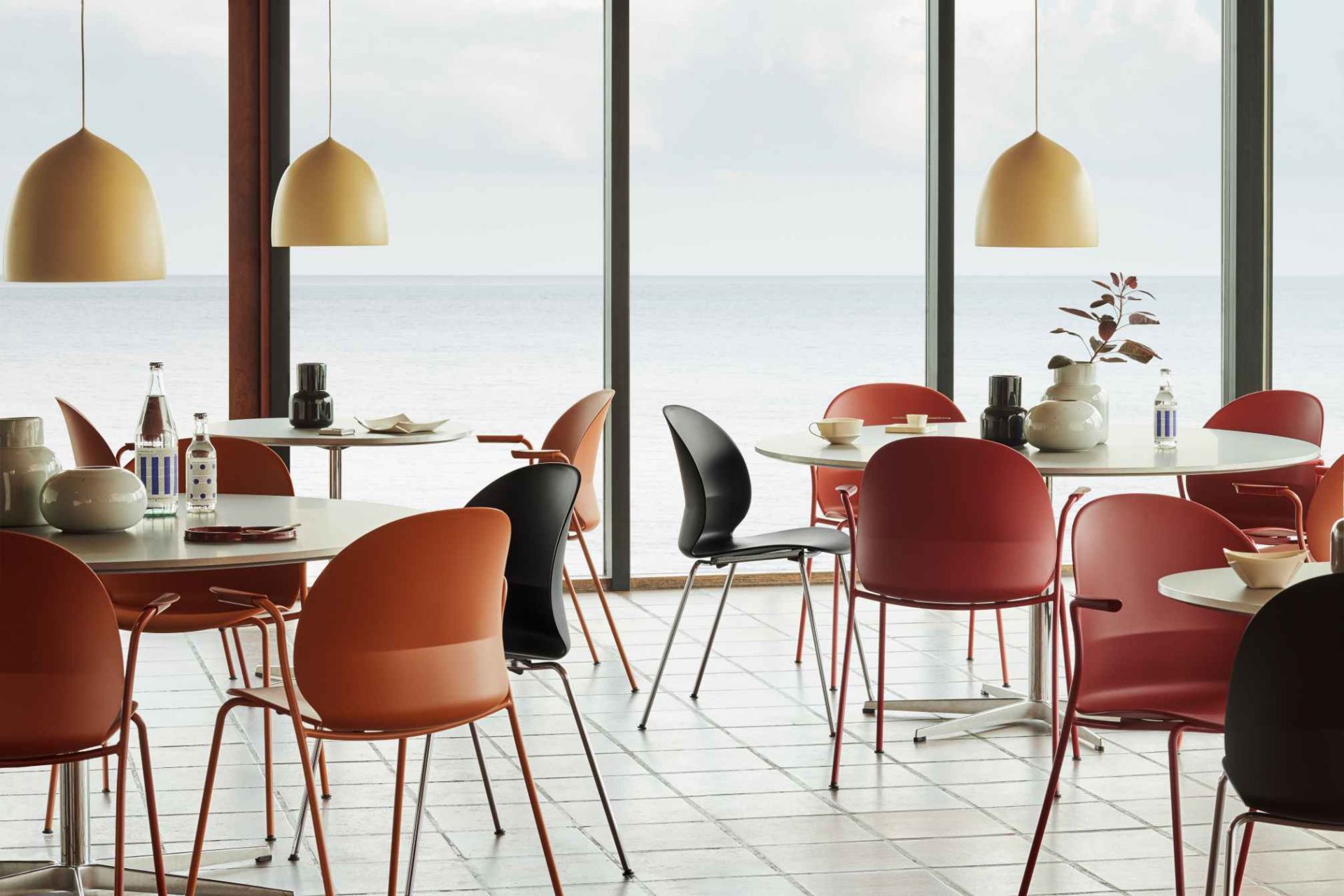 Innenaufnahme eines hellen Raumes mit Tischen und Fritz Hansen N02 Recycle Stühlen in verschiedenen Farben.