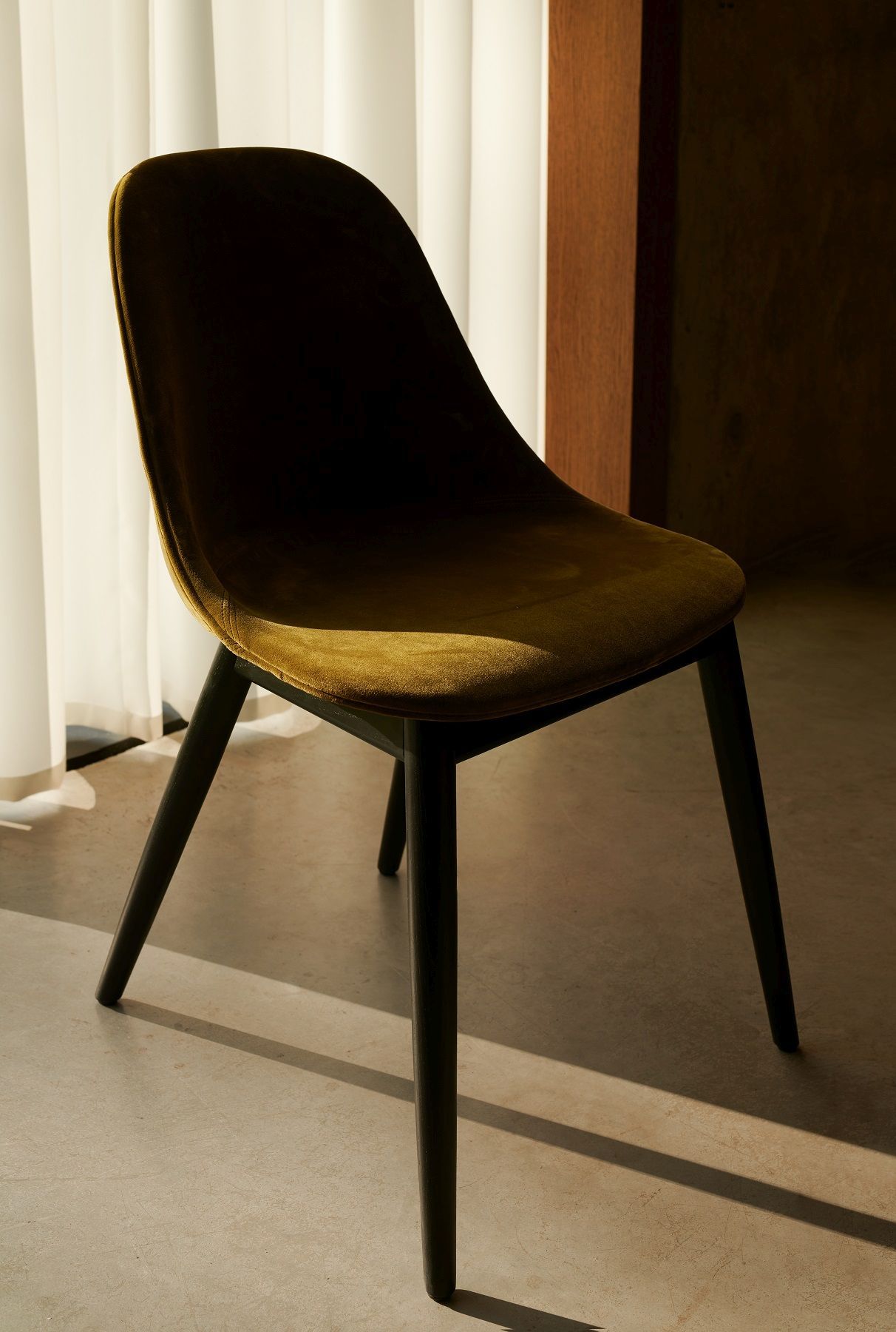 Nahaufnahme des Harbour Side Dining Chair Stuhls von Audo Copenhagen mit olivgrünem Samtbezug und schwarzen Holzbeinen.