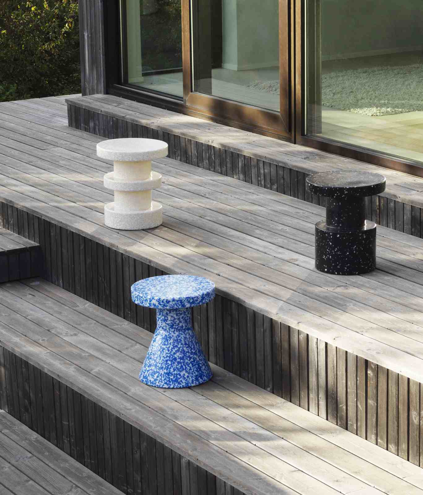 Drei Bit Stool Cone Hocker von Normann Copenhagen in Weiß, Schwarz und Blau auf einer Holzterrasse.