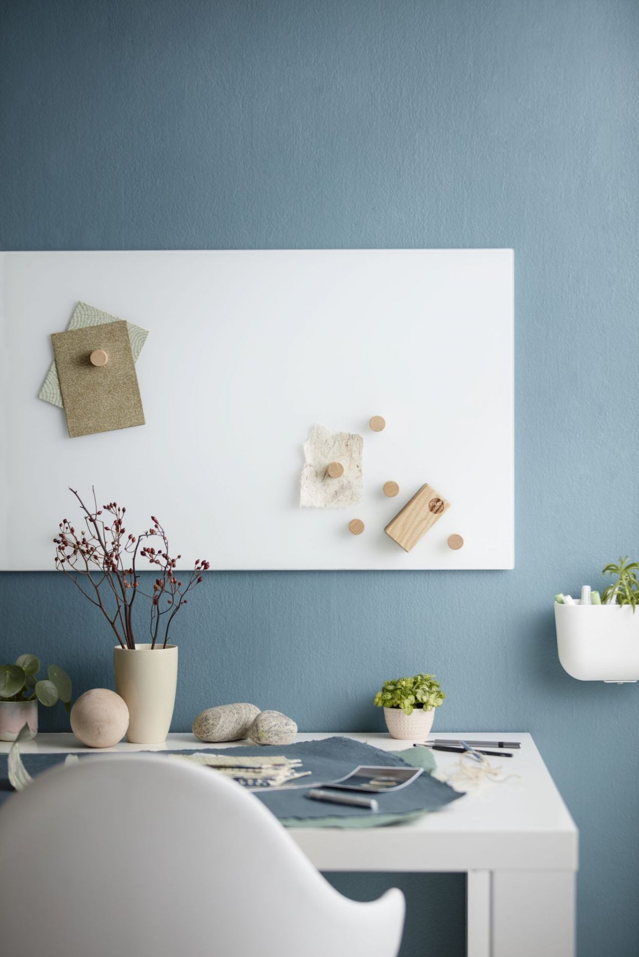 Chat Board Classic: Weiße magnetische Glastafel an blauer Wand mit Büroaccessoires.