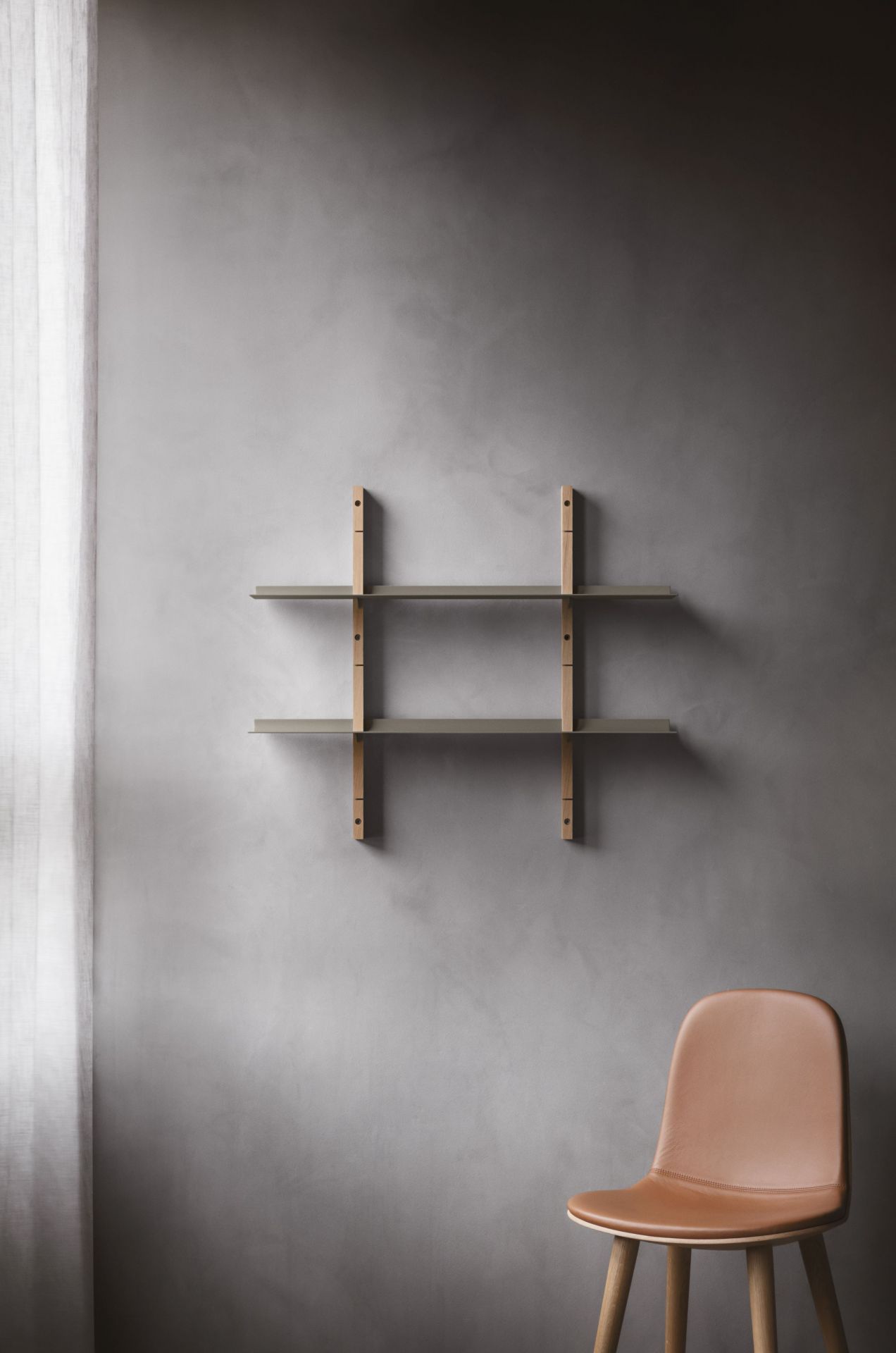 EVA SOLO Abalone Stuhl aus Eiche mit braunem Ledersitz vor grauer Wand. Designstuhl.