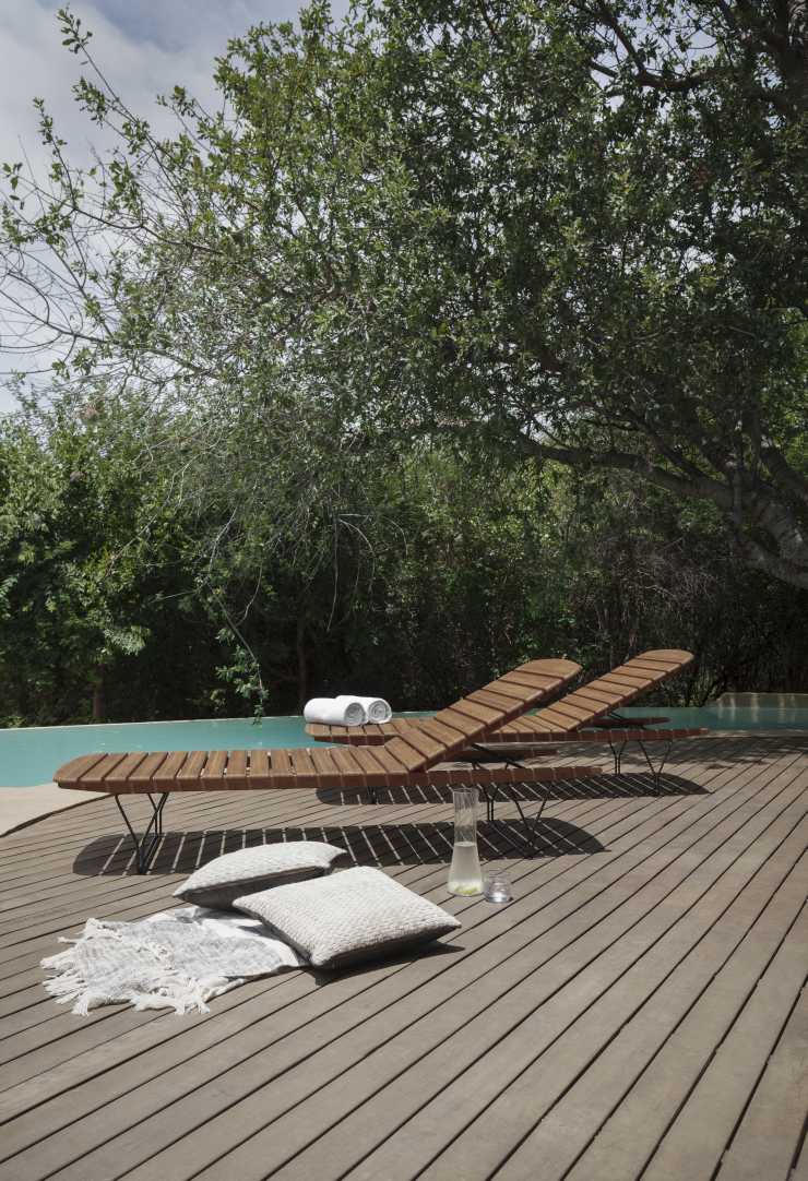 Molo Sonnenliege von Houe aus Holz am Pool mit Kissen und Handtüchern für entspannte Stunden.