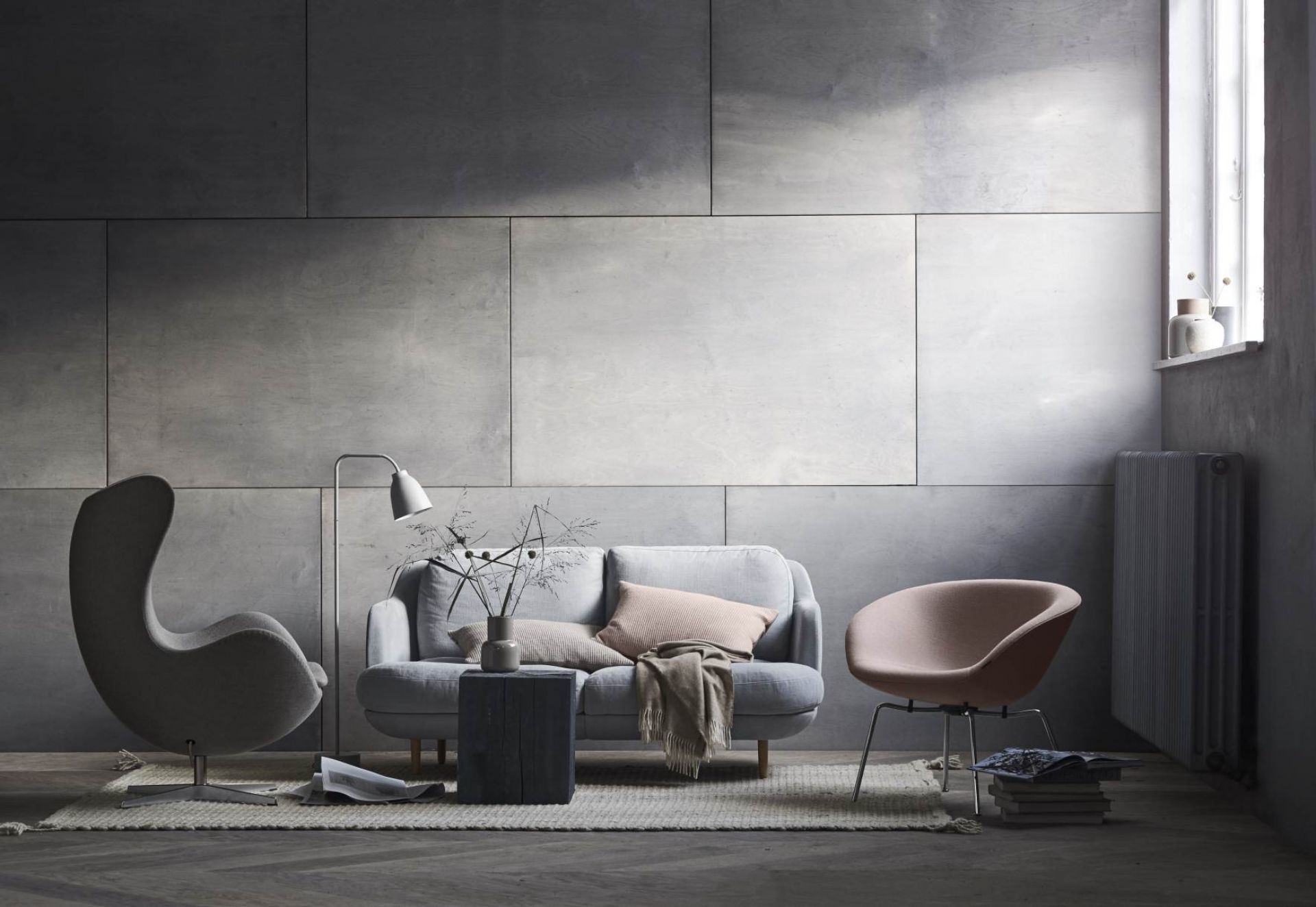 Wohnzimmer Interieur mit grauem Fritz Hansen Pot Sessel, Sofa und Designermöbeln auf einem Teppich.