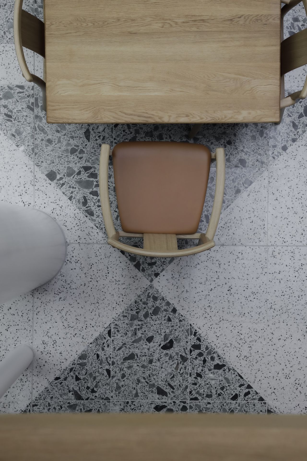 Draufsicht auf Audo Copenhagen Merkur Dining Chair Stuhl mit Armlehnen am Holztisch, Esszimmerstuhl mit braunem Sitz.