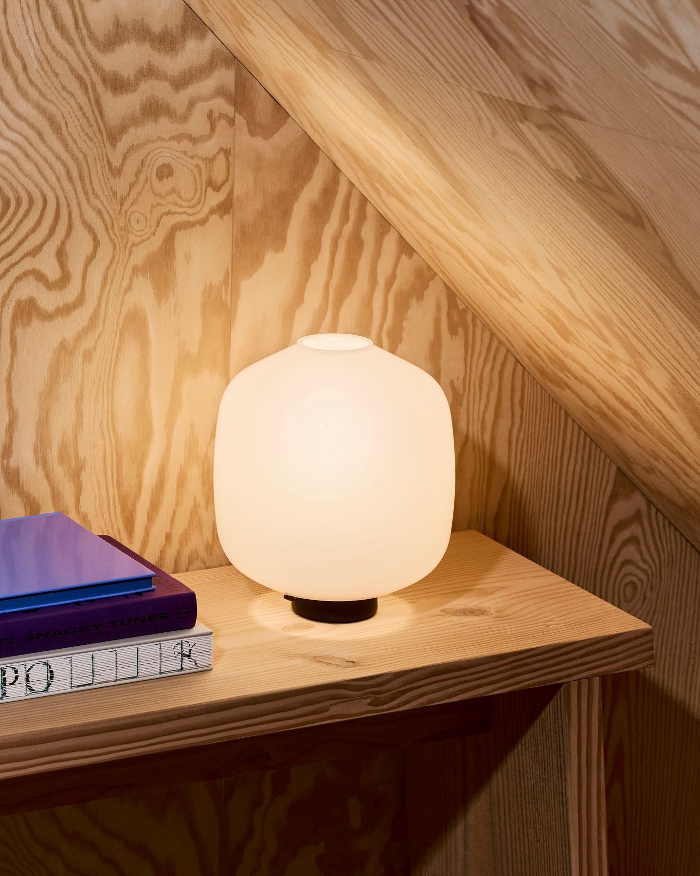 Nahaufnahme der Aspekt Buoy Tischleuchte von Hay, mit sanftem Licht auf einem Holztisch.