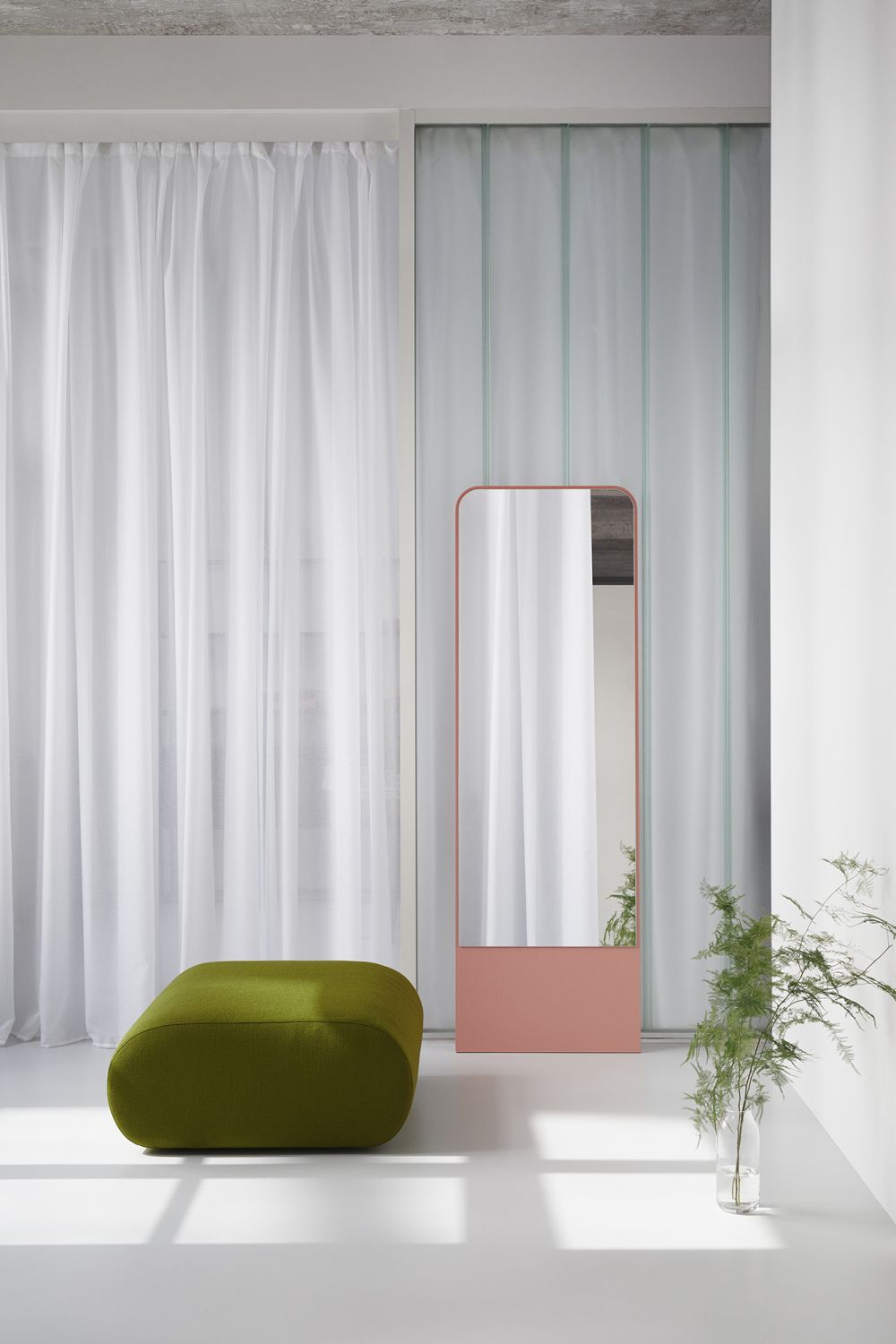 Grüner OLA Sofa Pouf OUT im minimalistischen Raum mit Spiegel und Vorhängen.