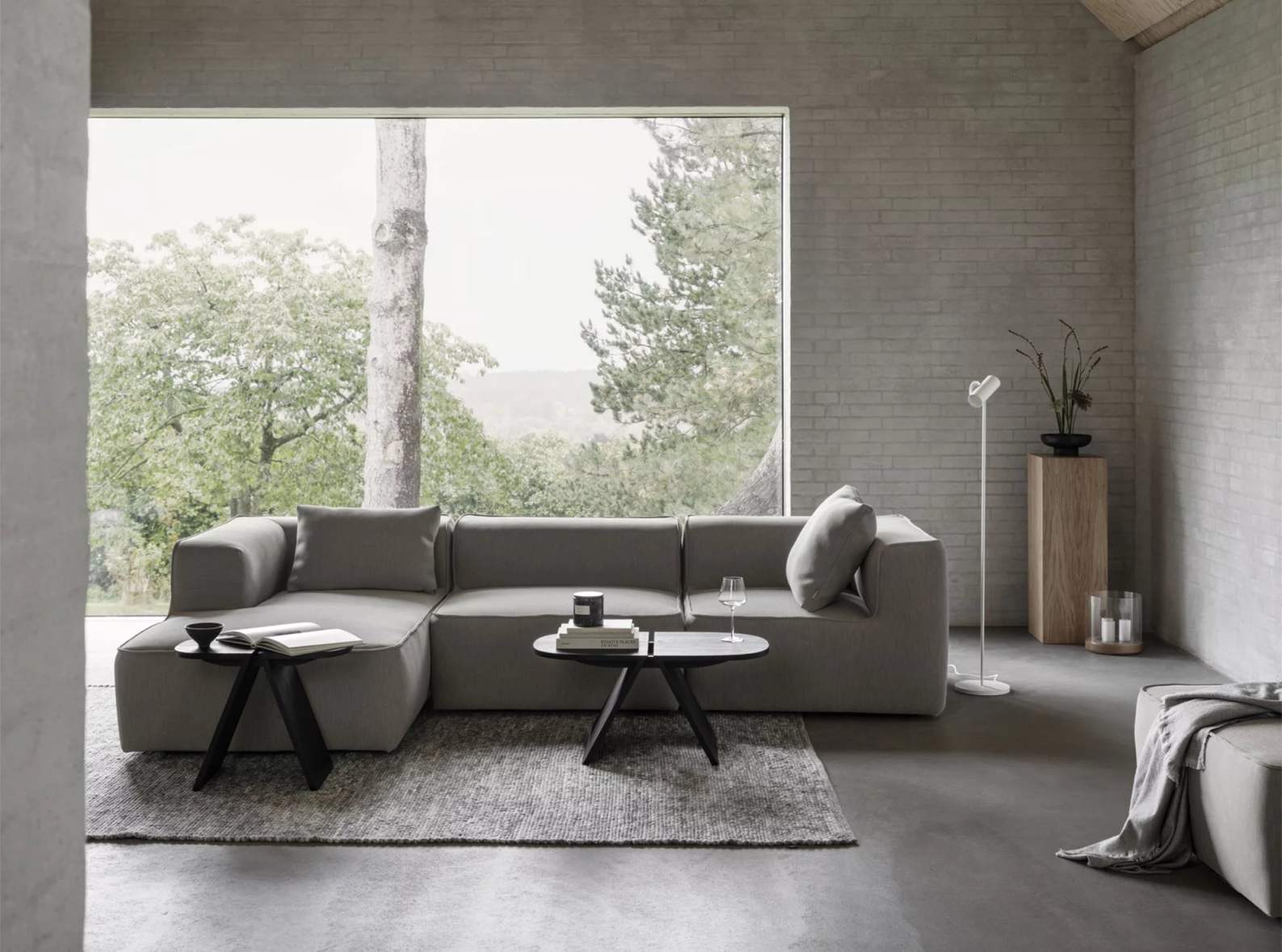 Avio Beistelltisch von Blomus in Eiche Schwarz neben einem grauen Sofa im modernen Wohnzimmer.