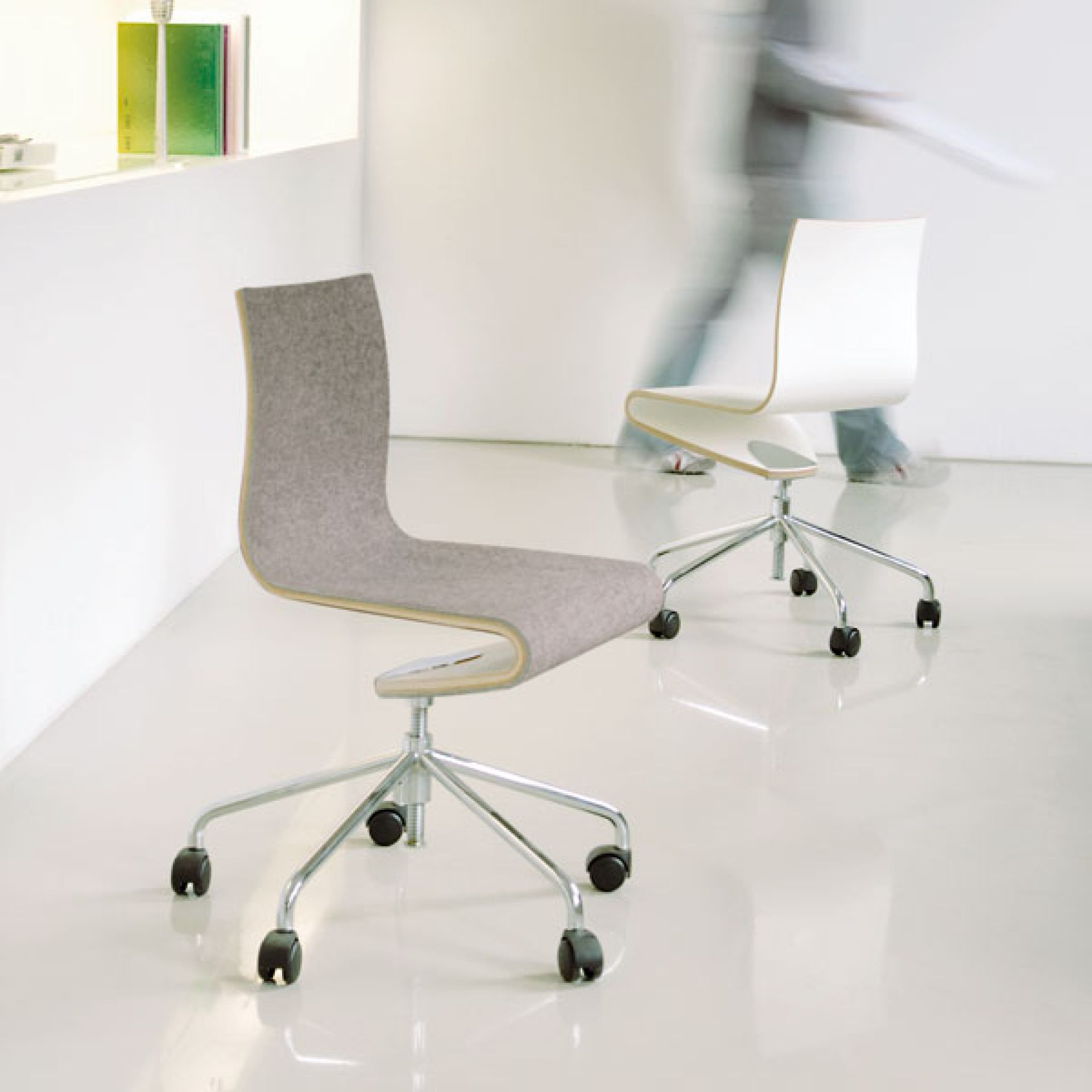 Moderner Bürostuhl mit grauem Filzbezug und Chromgestell auf Rollen, minimalistisches Design.