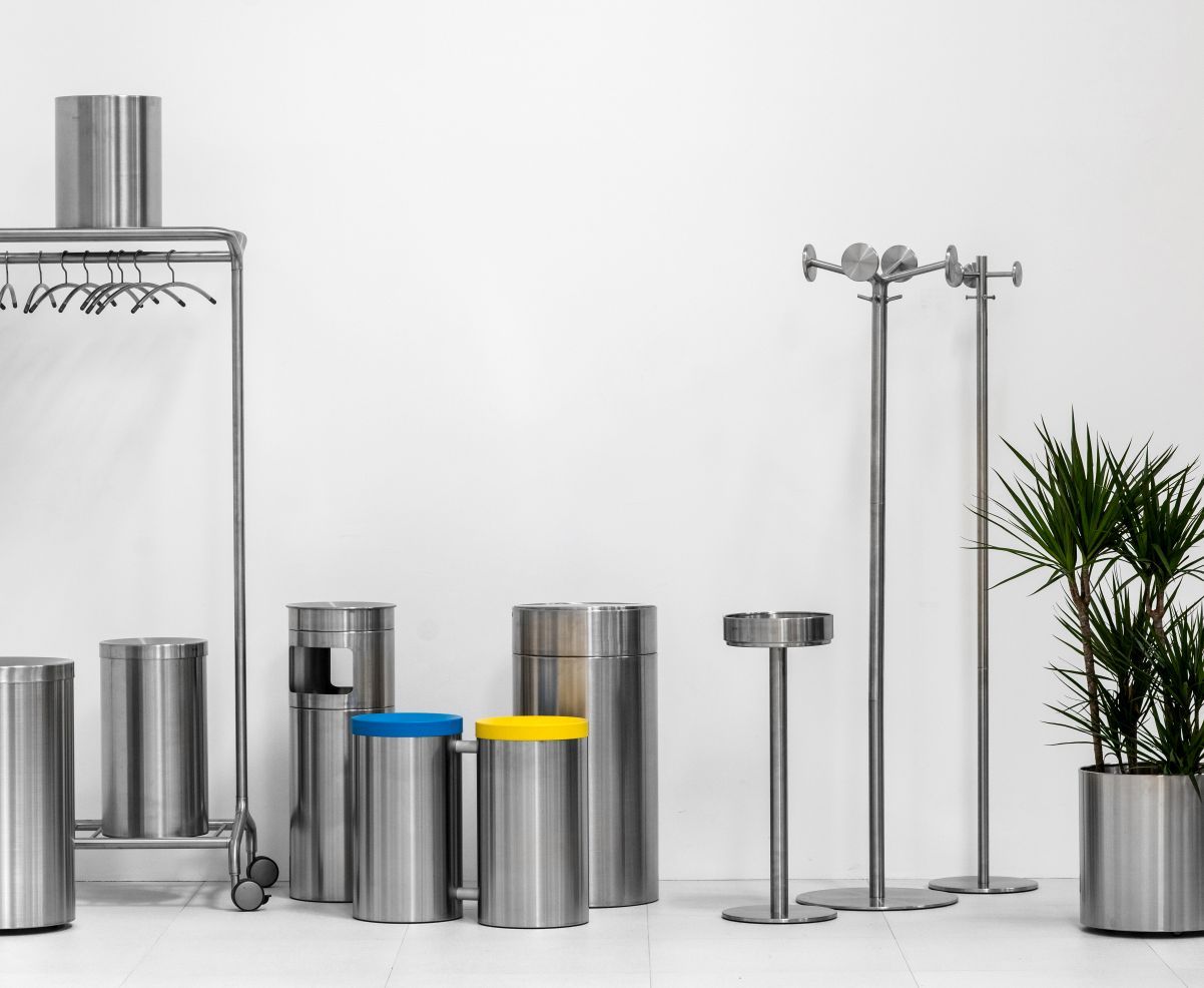 Nox Vesta Kleiderbügelständer von Rexite und weitere Edelstahl-Garderobenmöbel wie Aschenbecher und Mülleimer vor weißem Hintergrund.