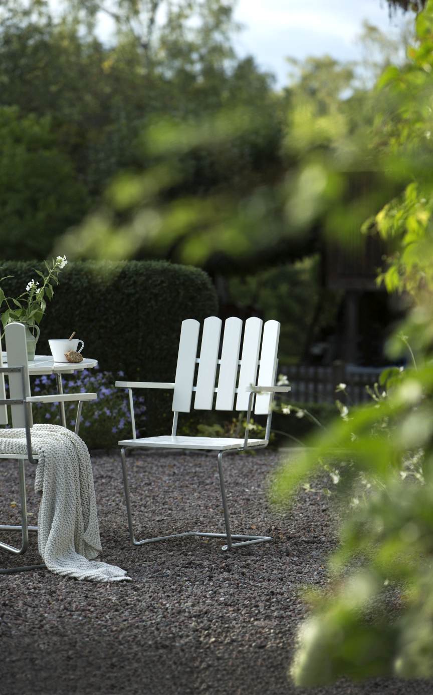 Grythyttan Stalmöbler A2 Armlehnstuhl im Garten: Weißer Teakholz Stuhl mit Armlehnen für den Außenbereich.