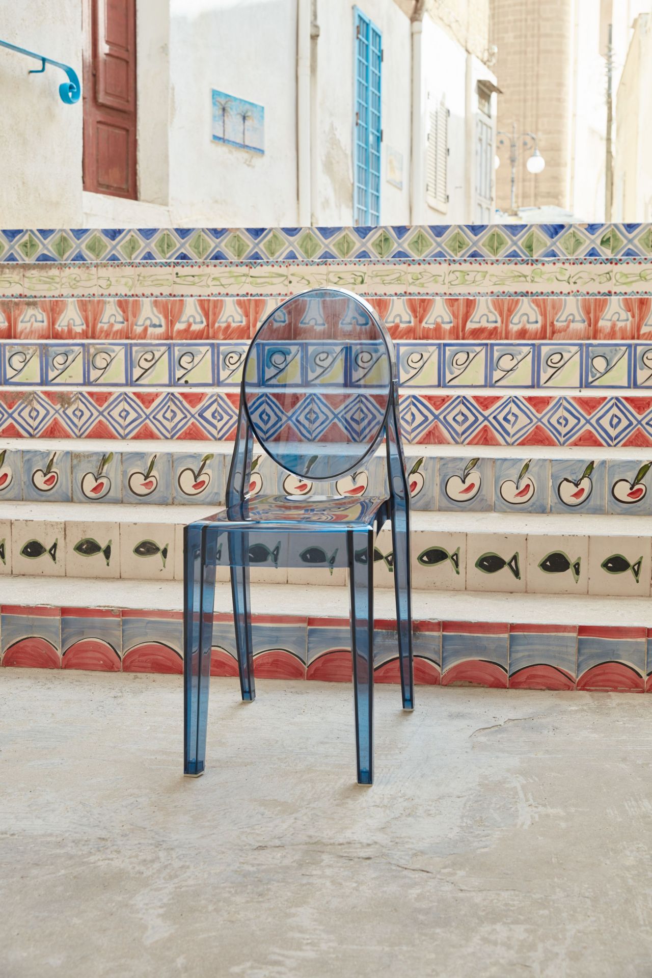 Victoria Ghost Stuhl von Kartell, glasklar, auf einer Treppe mit bunten Fliesen. Designklassiker für modernes Wohnen.