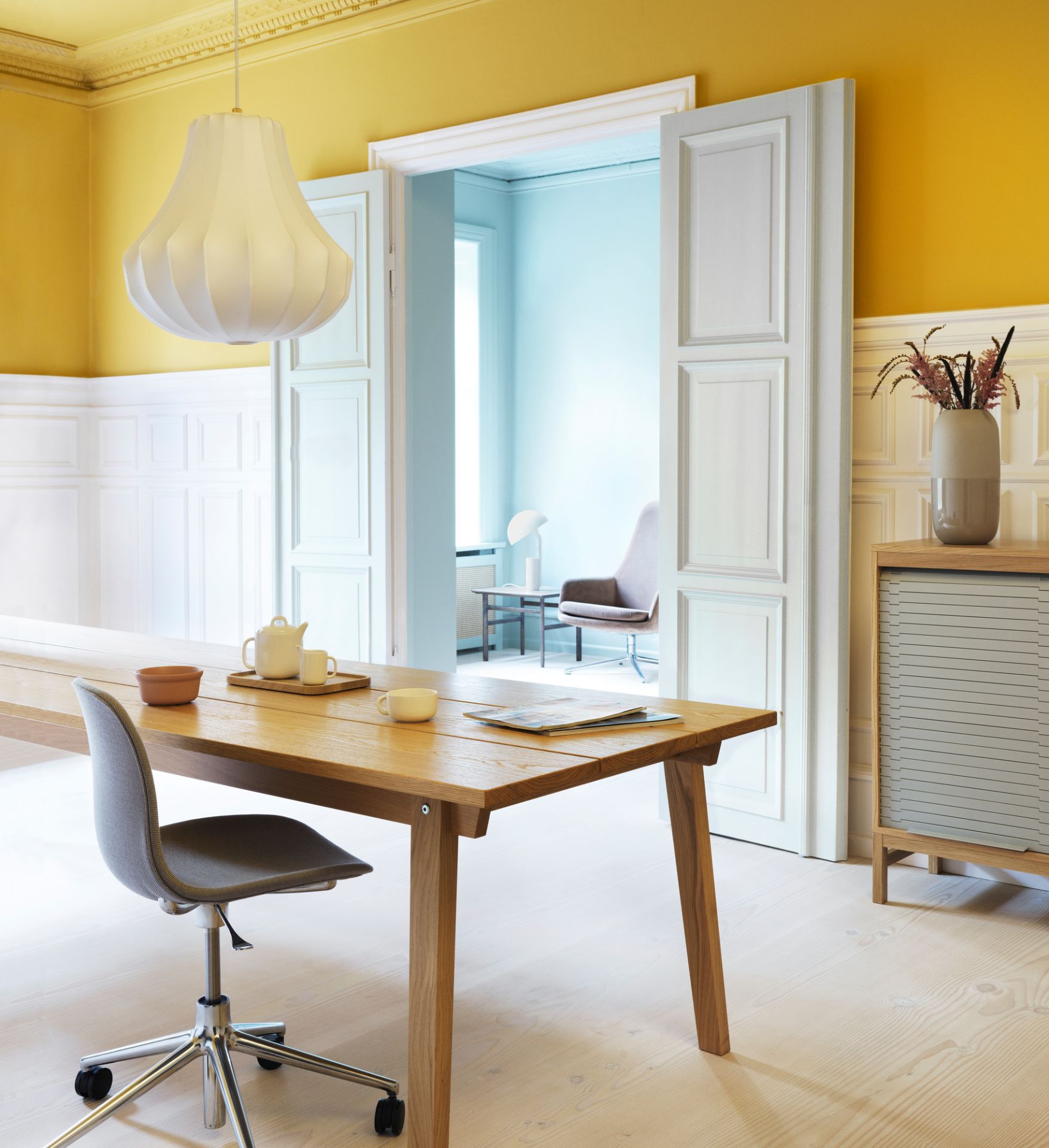 Nahaufnahme der Normann Copenhagen Phantom Lampe, einer modernen Pendelleuchte über einem Holztisch in einem stilvollen Interieur.