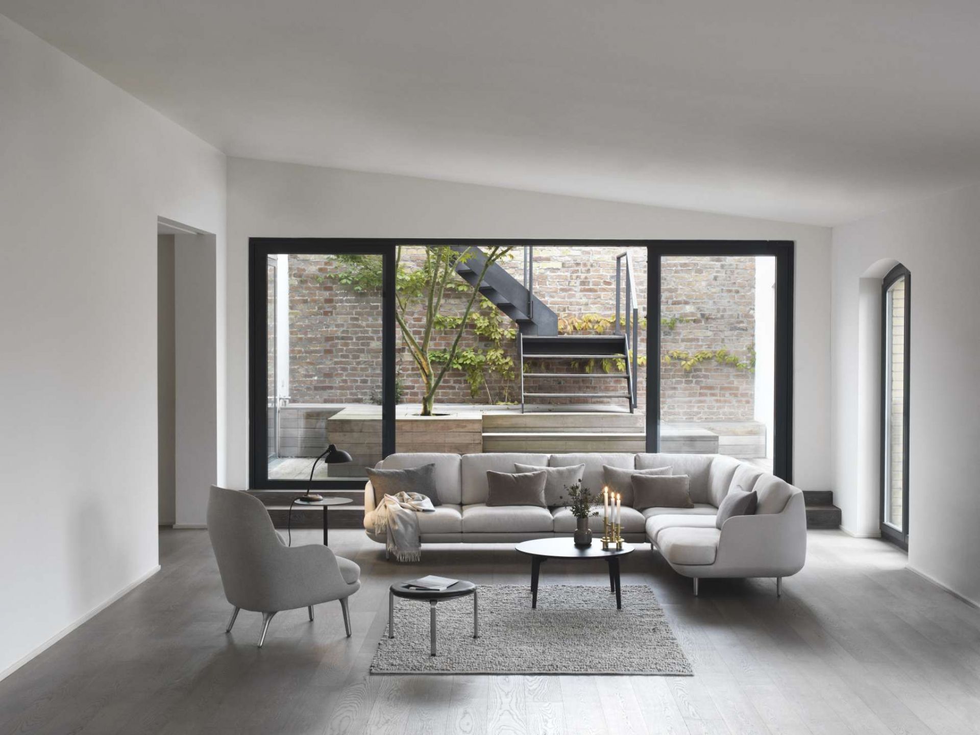 Heller Wohnraum mit großem Sofa, Couchtisch und Fri Sessel von Fritz Hansen in Grau.