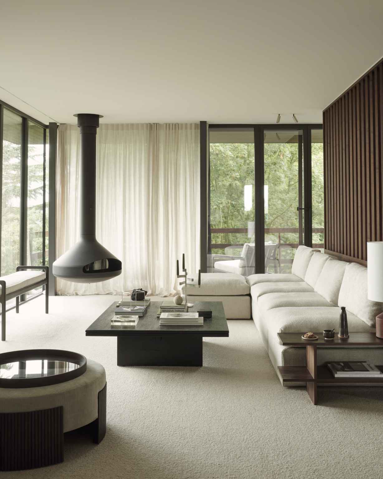 Wohnzimmer mit Ethnicraft Couchtisch Grooves, schwarzer Holztisch mit Rillenmuster, hellem Sofa und Kamin.