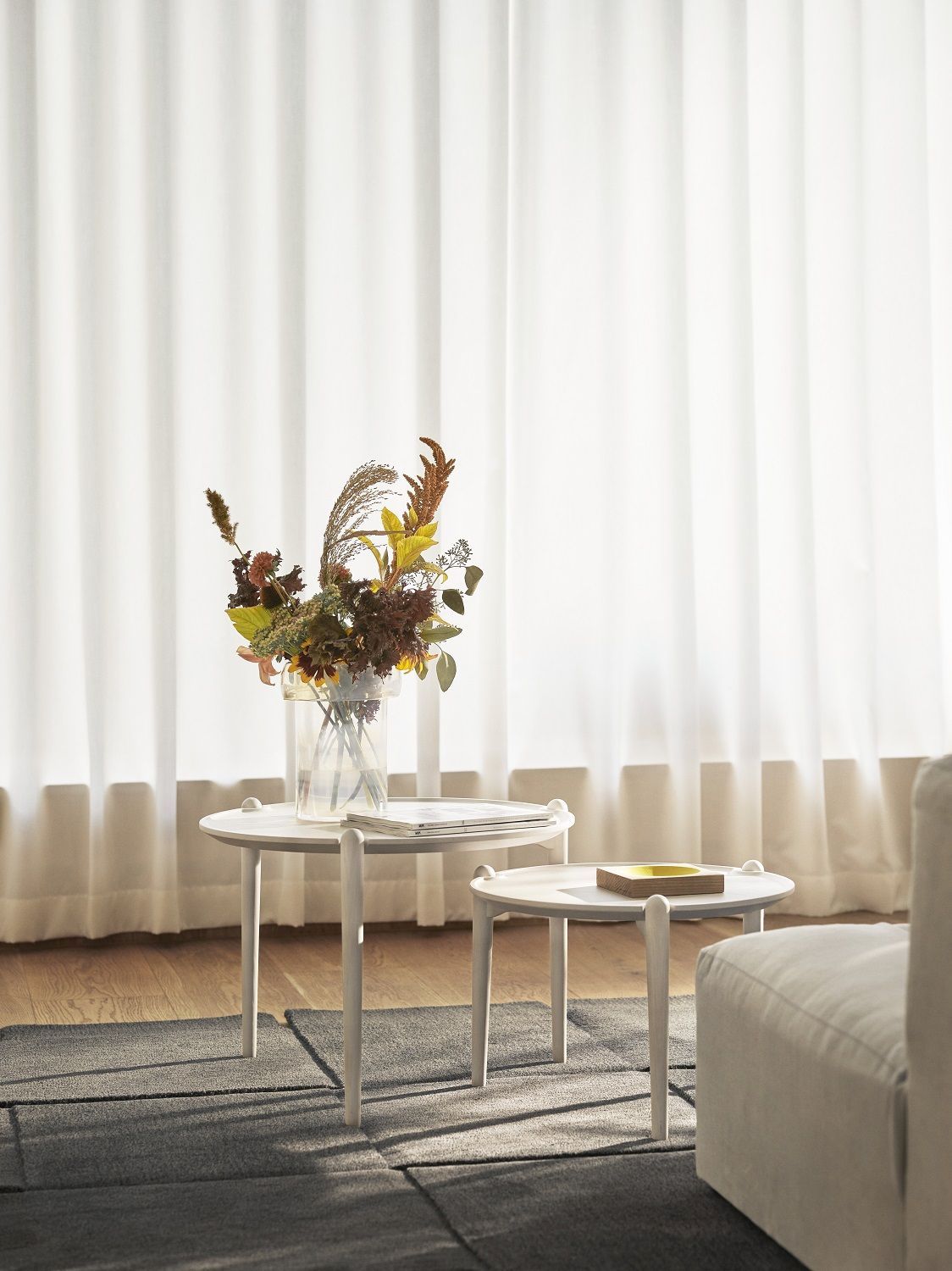 Zwei weiße Aria Table Beistelltische von Design House Stockholm mit Dekoration im Wohnzimmer.