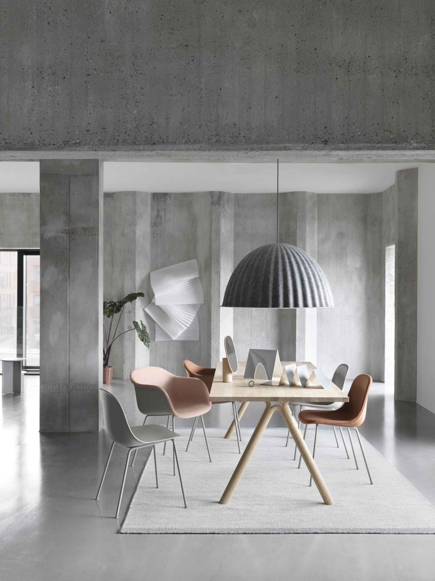 Graue Under The Bell Pendelleuchte von Muuto über Esstisch mit Stühlen in modernem Interieur.