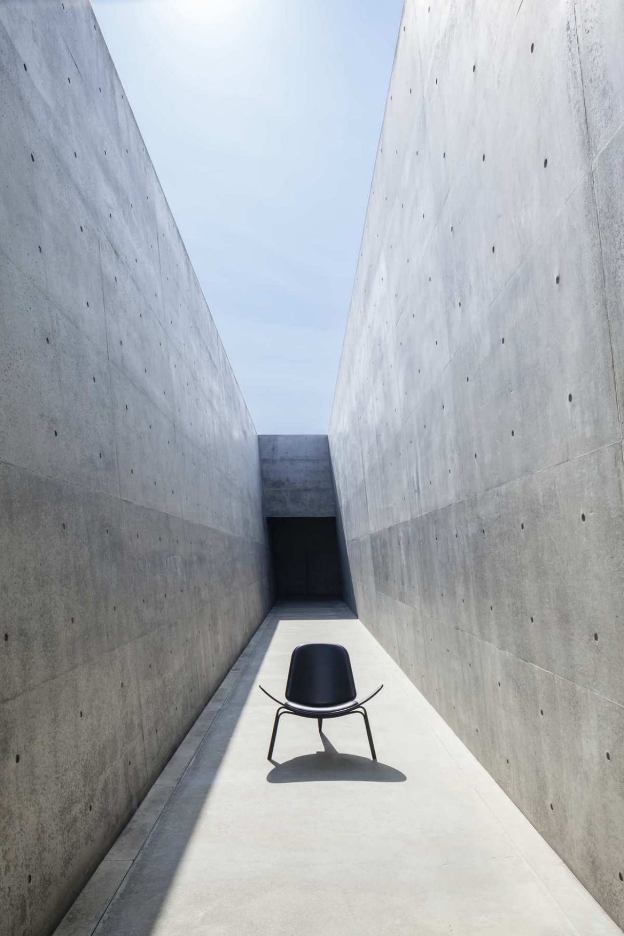 Schwarzer CH07 Shell Chair Stuhl von Carl Hansen & Søn in minimalistischer Betonumgebung. Designklassiker.