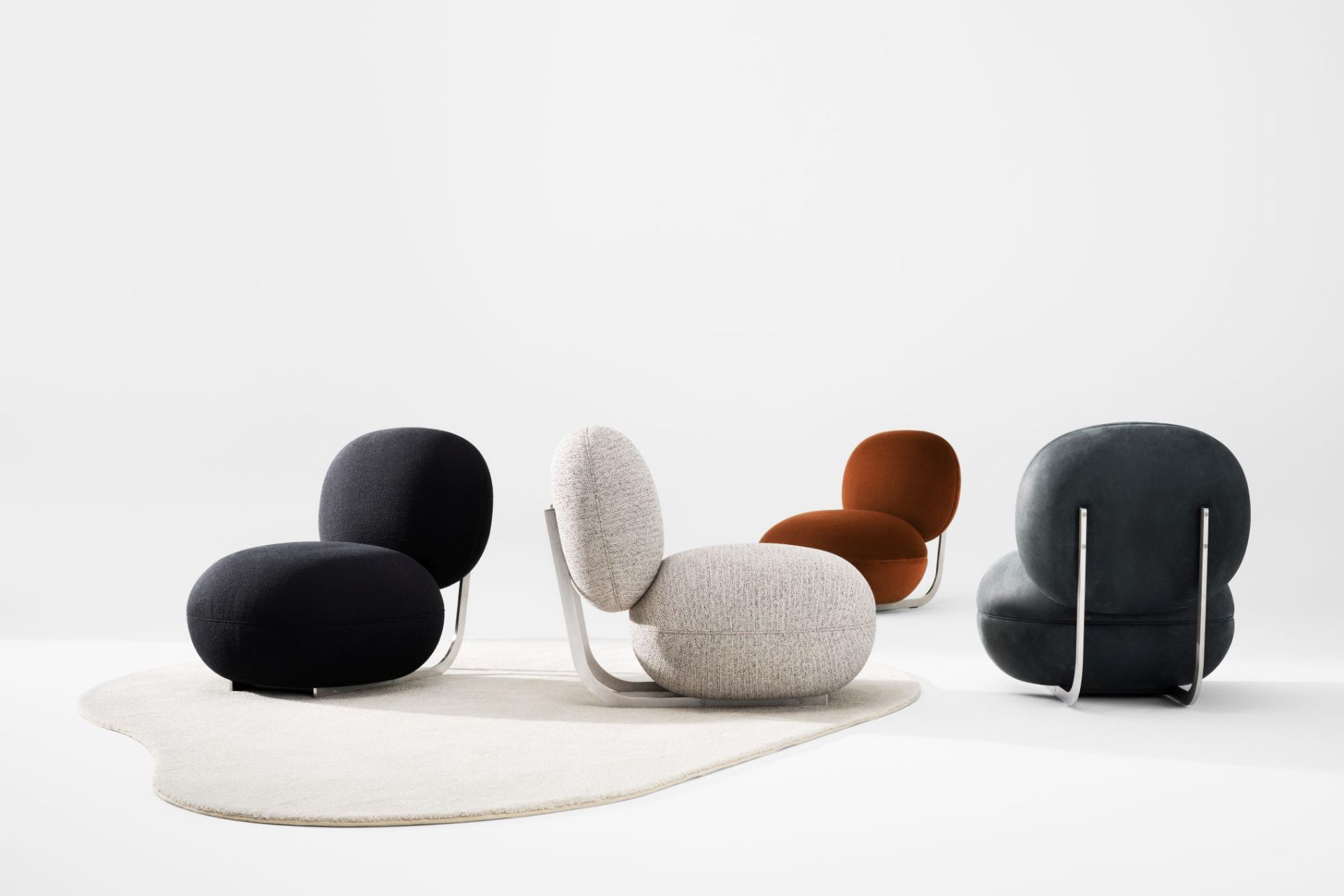 NORR11 Copper Lounge Sessel mit Edelstahlgestell in Schwarz, Beige, Braun und Grau auf Teppich.