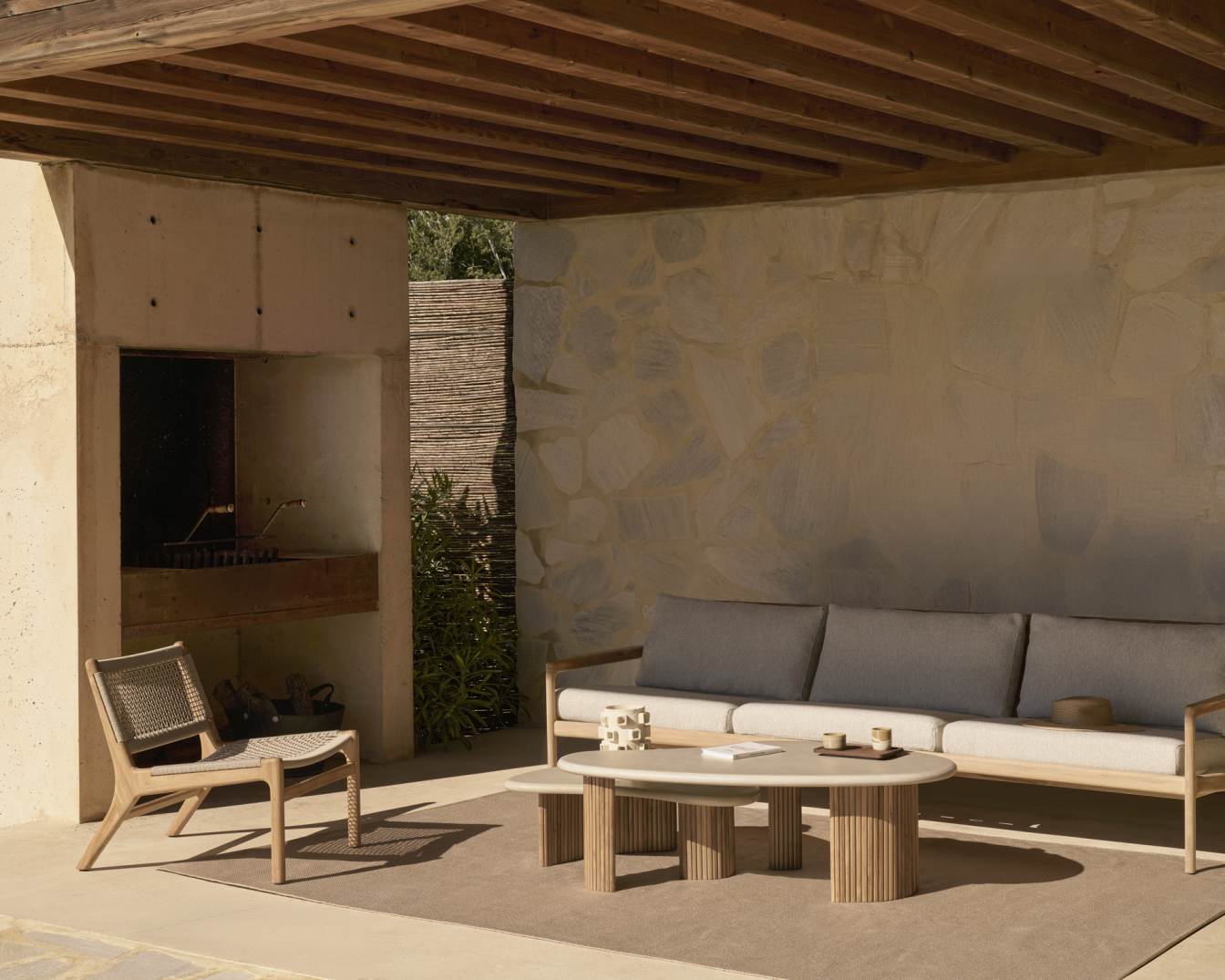 Ethnisch gestalteter Outdoor-Bereich mit Ethnicraft Jack Loungesessel aus Teakholz und beiger Kordel, Sofa und Couchtisch.