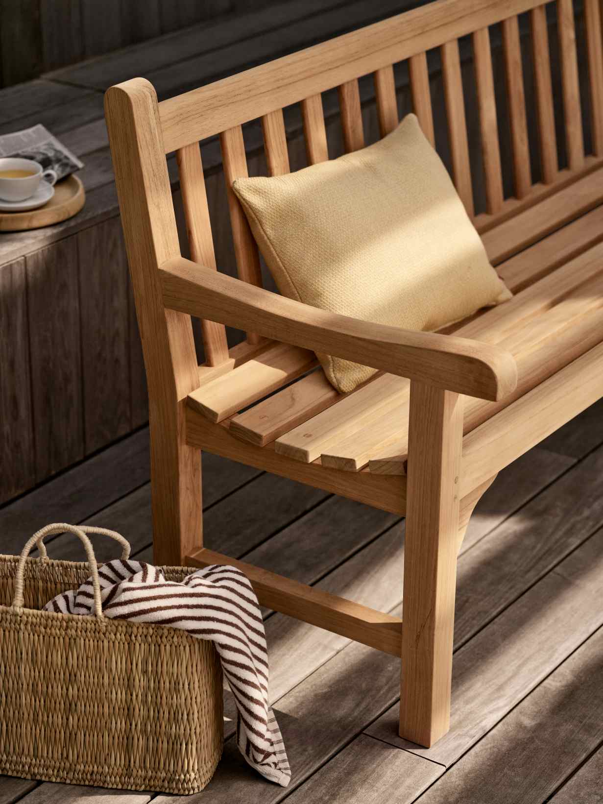 Nahaufnahme der Skagerak England Bank aus Teakholz mit Kissen und Strandtasche.